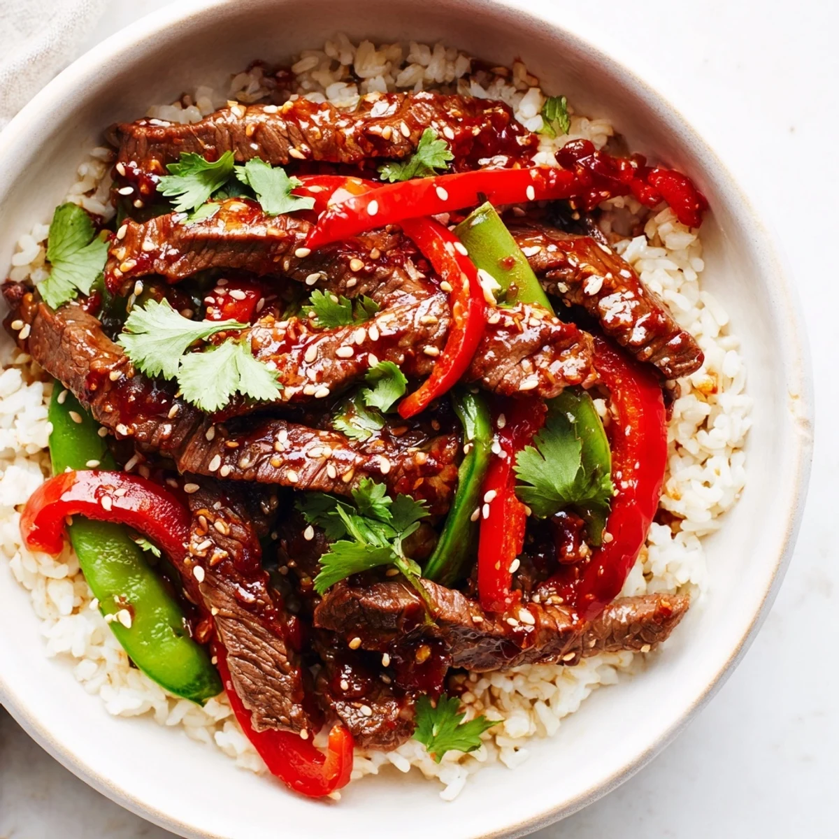 A close-up shows the savory Spicy Beef Bowl topped with sesame seeds and fresh cilantro, ready to satisfy spice-loving dinner cravings. 