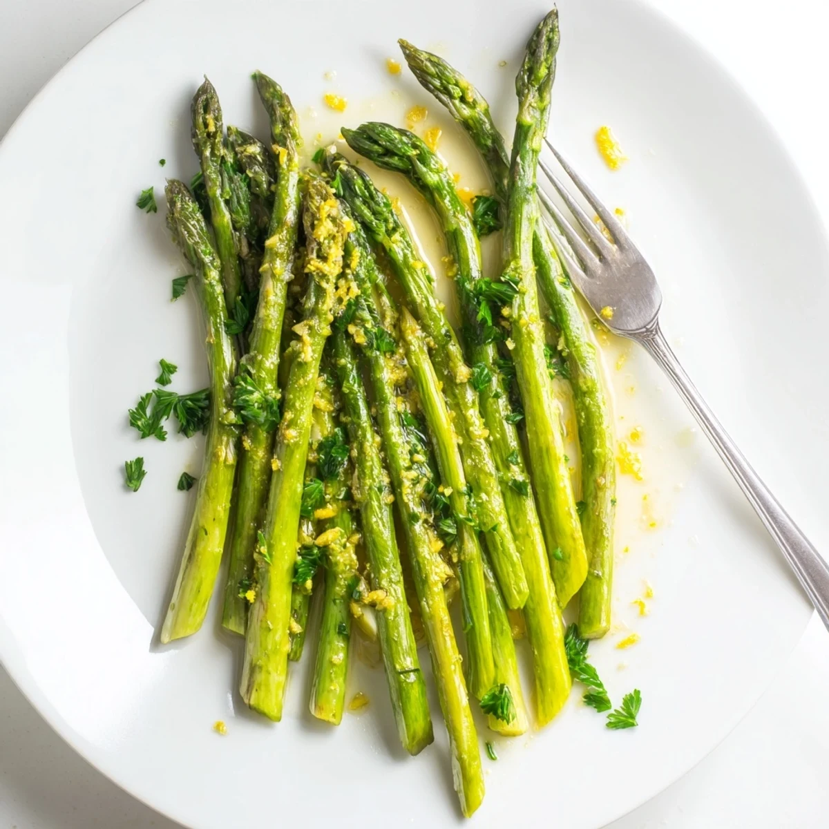 A close-up of Lemon Garlic Asparagus shows crisp-tender spears coated in melted butter and minced garlic, finished with lemon juice for a zesty, savory flavor.