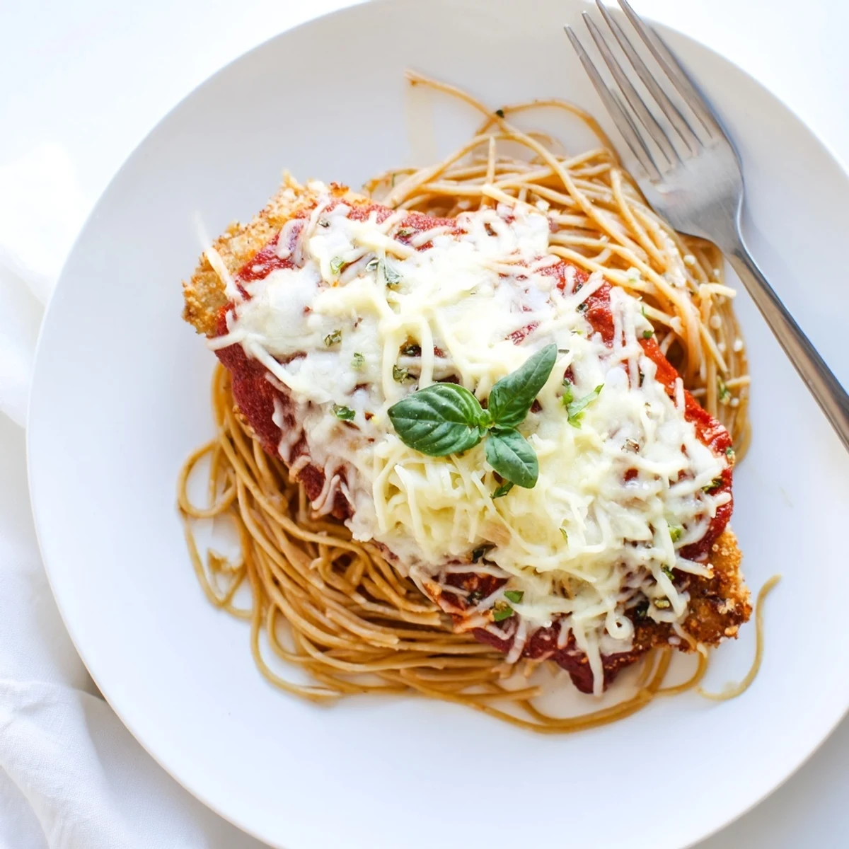 Hearty Italian-American chicken Parmesan over al dente spaghetti, featuring saucy marinara and a golden, cheesy chicken cutlet.