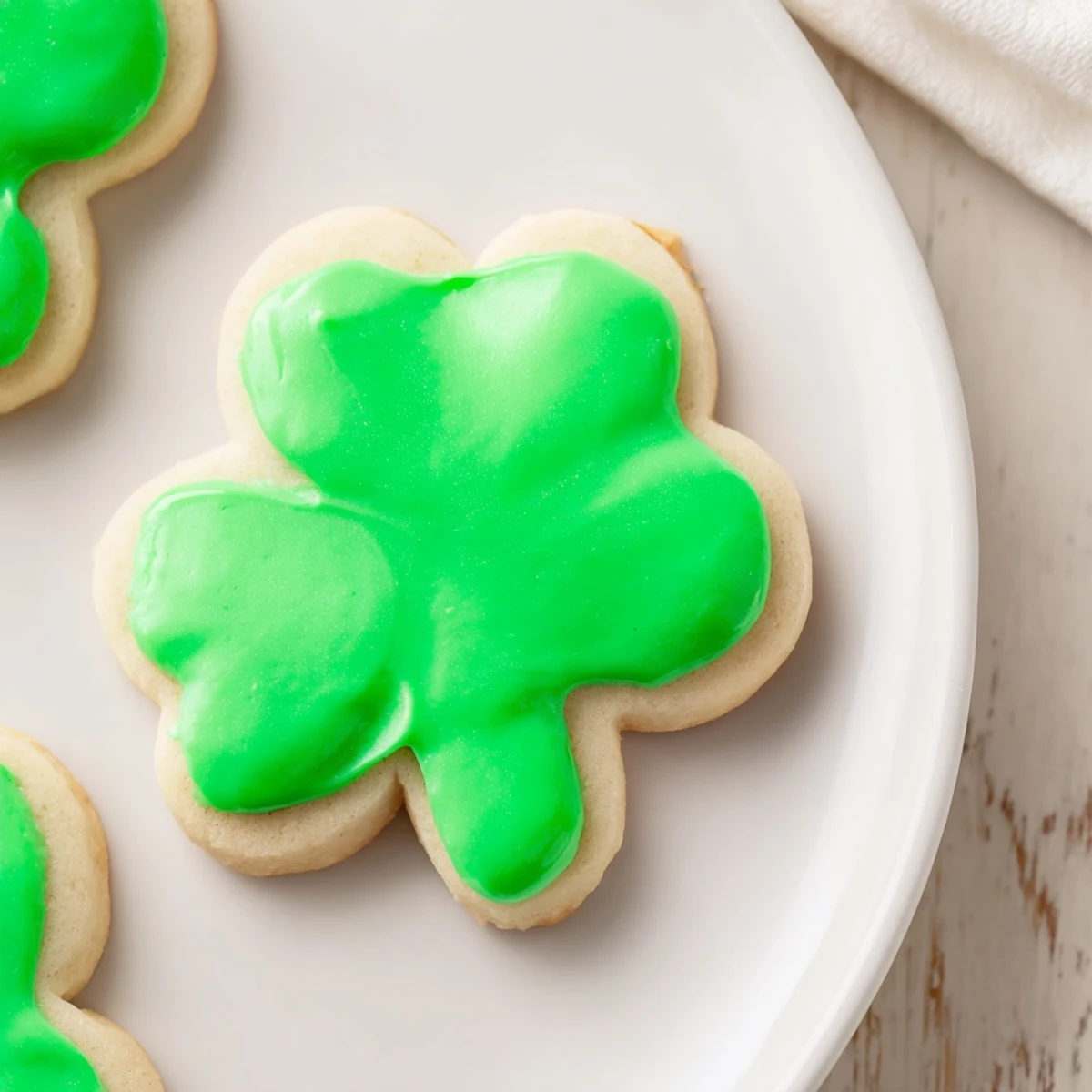 Close-up of Shamrock Sugar Cookies with Green Icing, showcasing the smooth, bright green icing against the buttery, golden-brown cookie base.