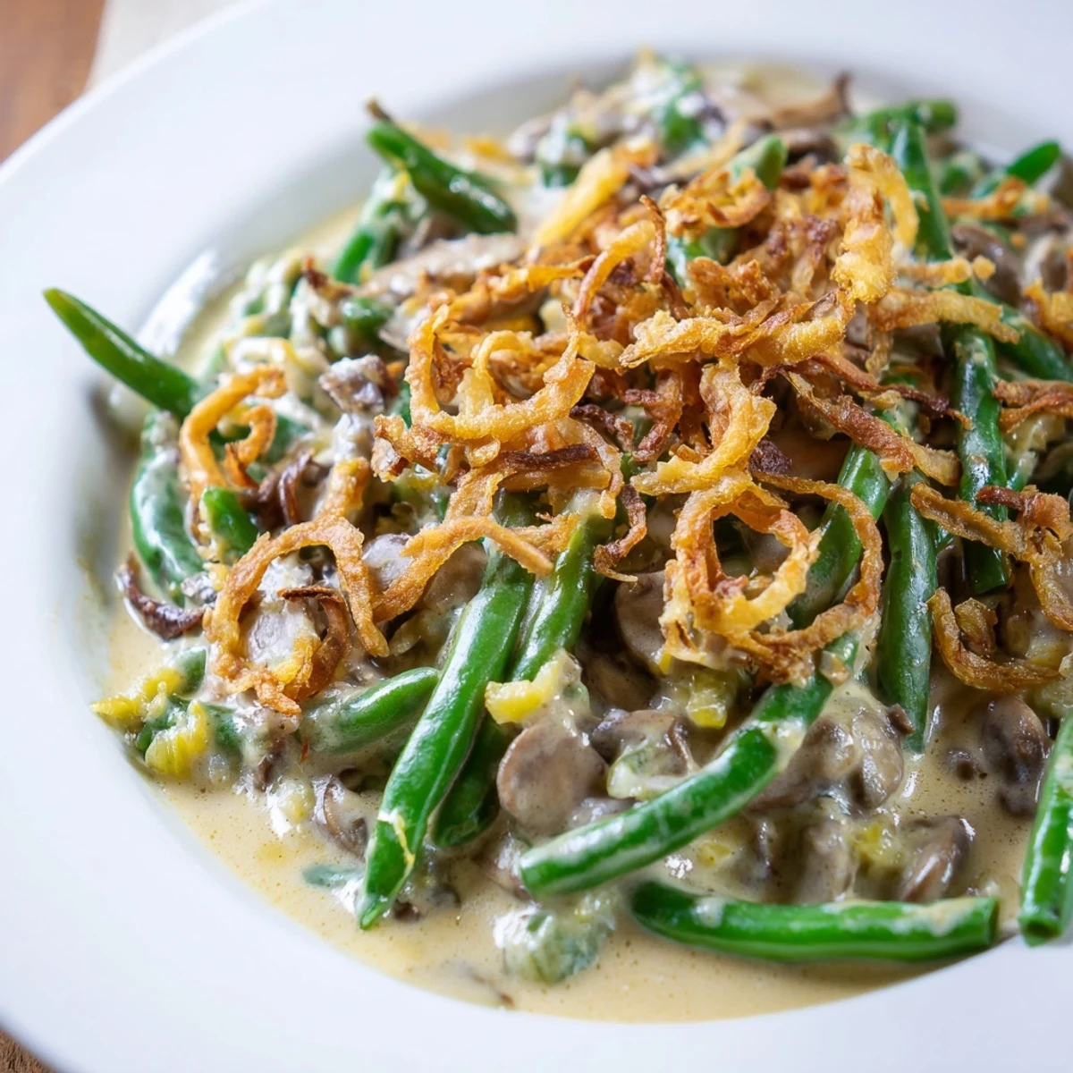 Freshly blanched green beans covered in a creamy mushroom sauce, topped with golden crispy fried onions in a white baking dish for Green Bean Casserole with Crispy Onions.