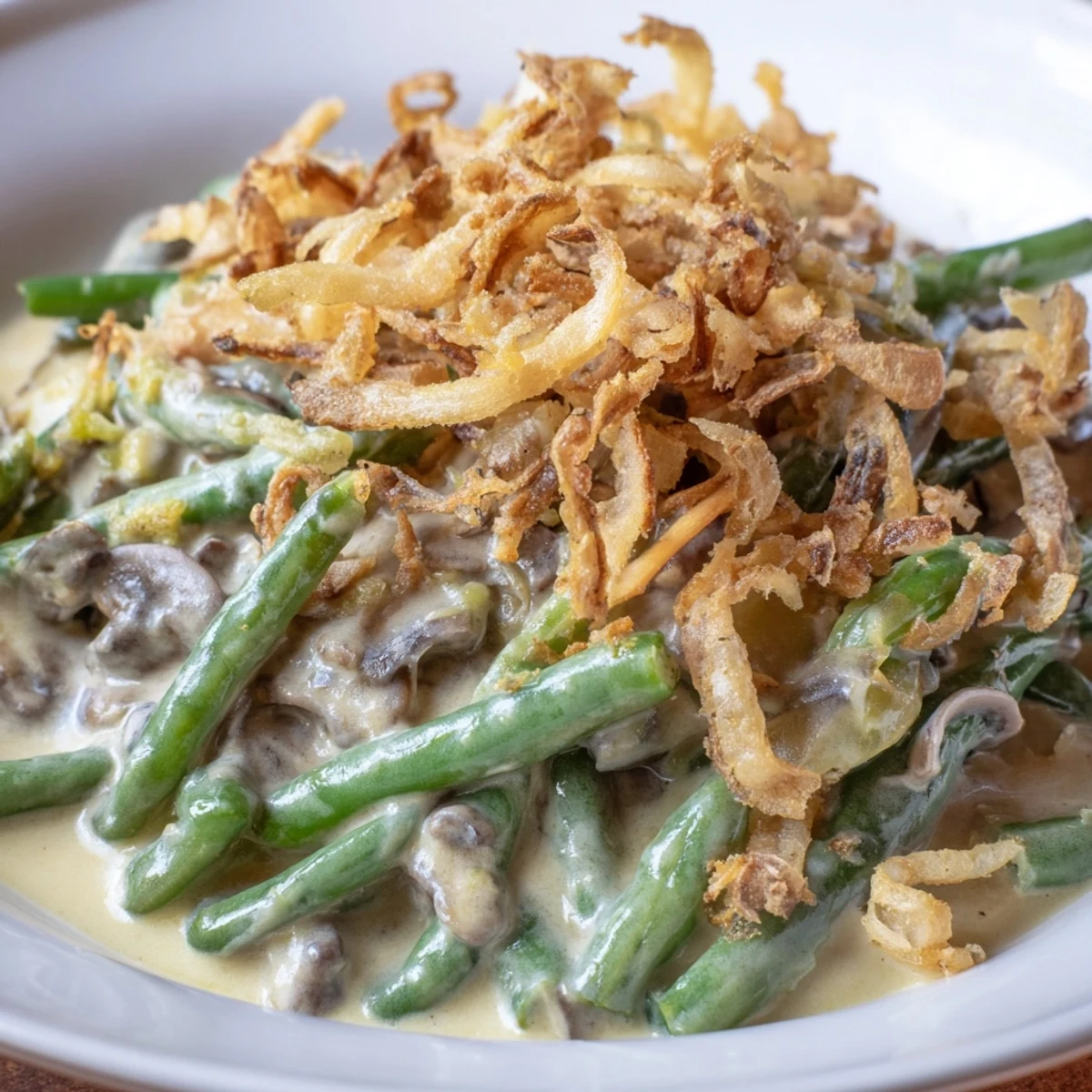 A spoon scooping a generous serving of Green Bean Casserole with Crispy Onions, revealing tender green beans and savory mushroom sauce beneath the crunchy onion topping.