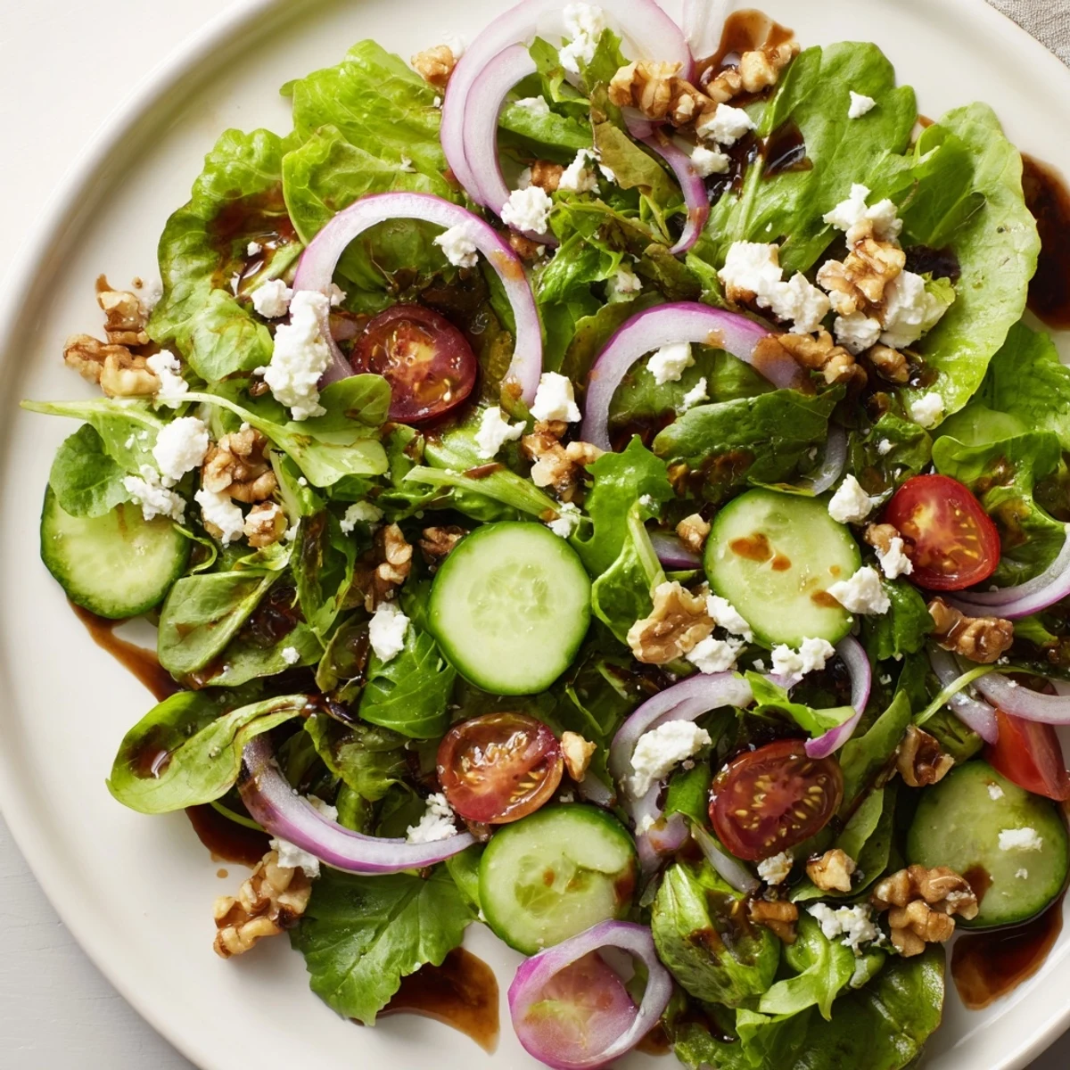A vibrant Spring Mix Salad with Vinaigrette topped with crumbled feta and toasted walnuts, served as a light lunch.