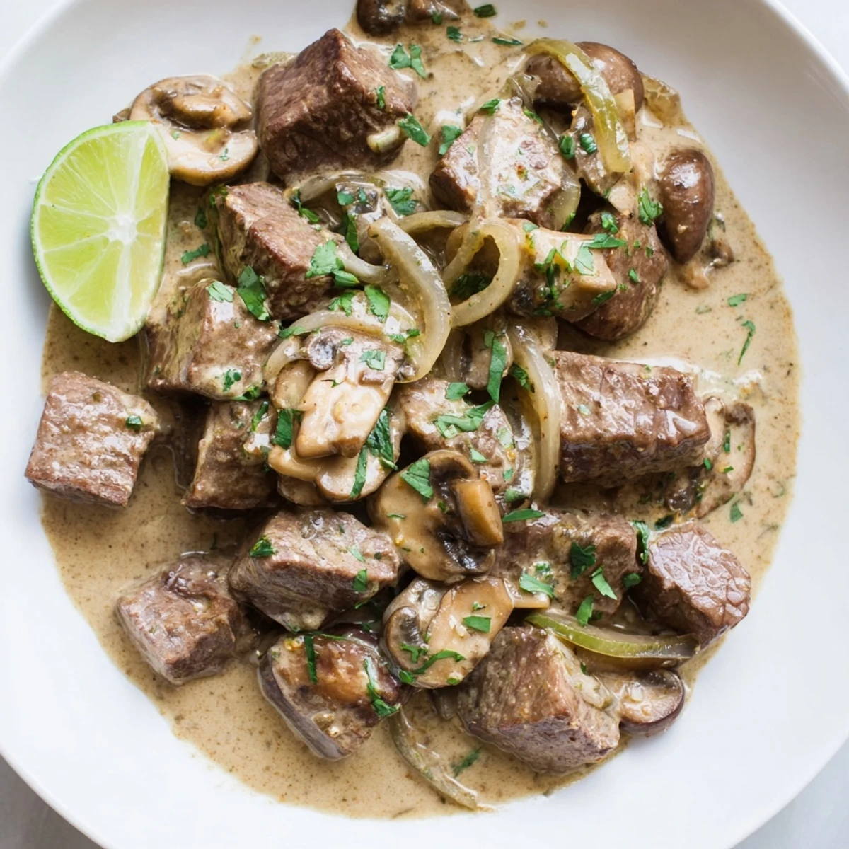 A close-up of Lemongrass Coconut Braised Beef with Mushrooms, showcasing tender beef chunks in a creamy sauce with carrots and herbs.