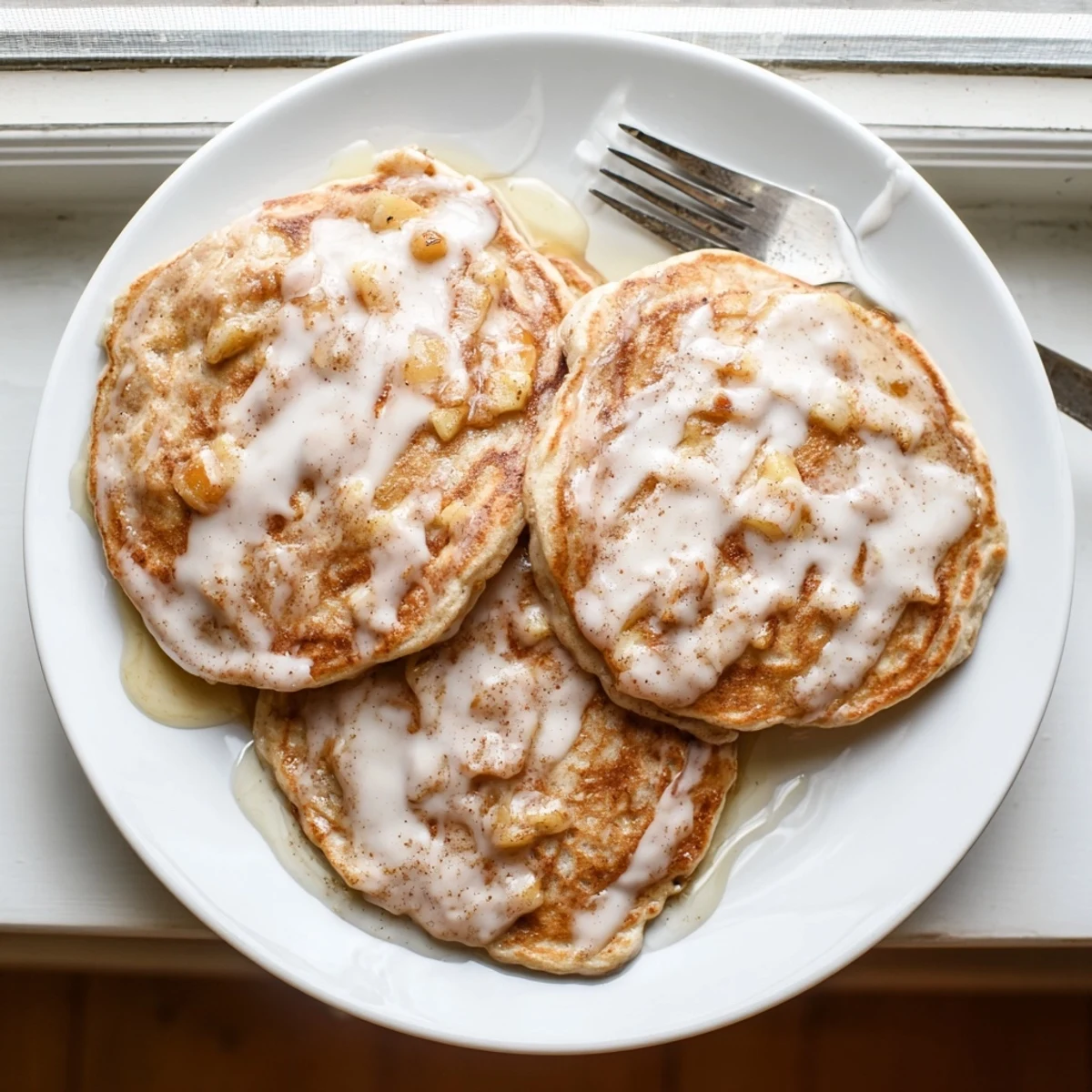 Fluffy Apple Fritter Pancakes with diced apples and cinnamon, served warm on a rustic plate.