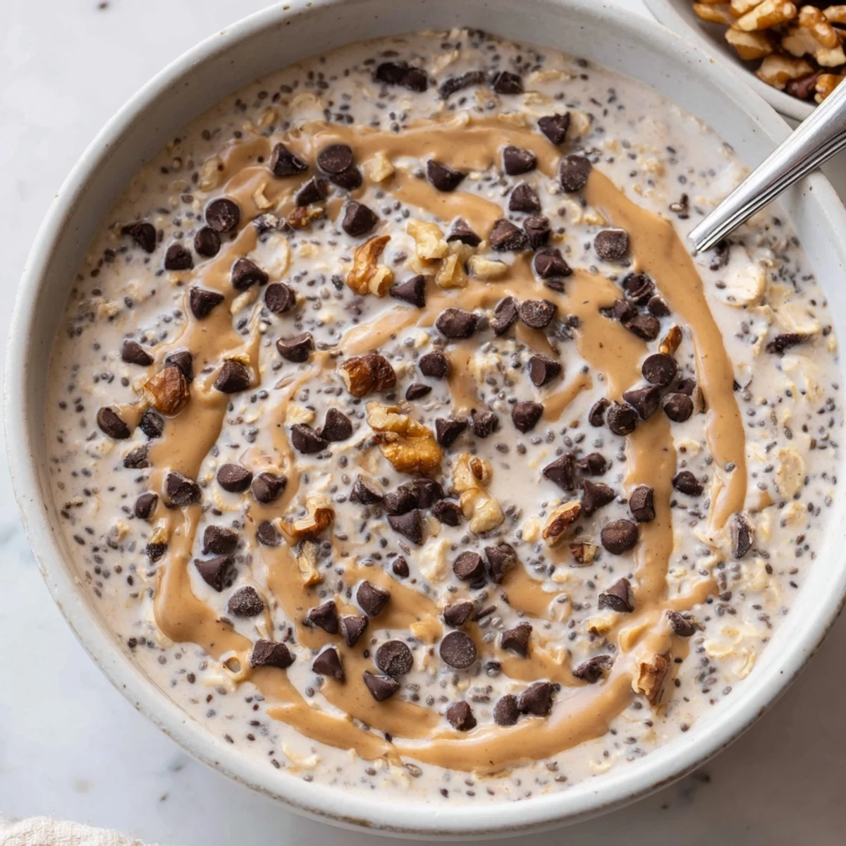 A serving of Cookie Dough Overnight Oats with chopped walnuts, ready to be enjoyed chilled.