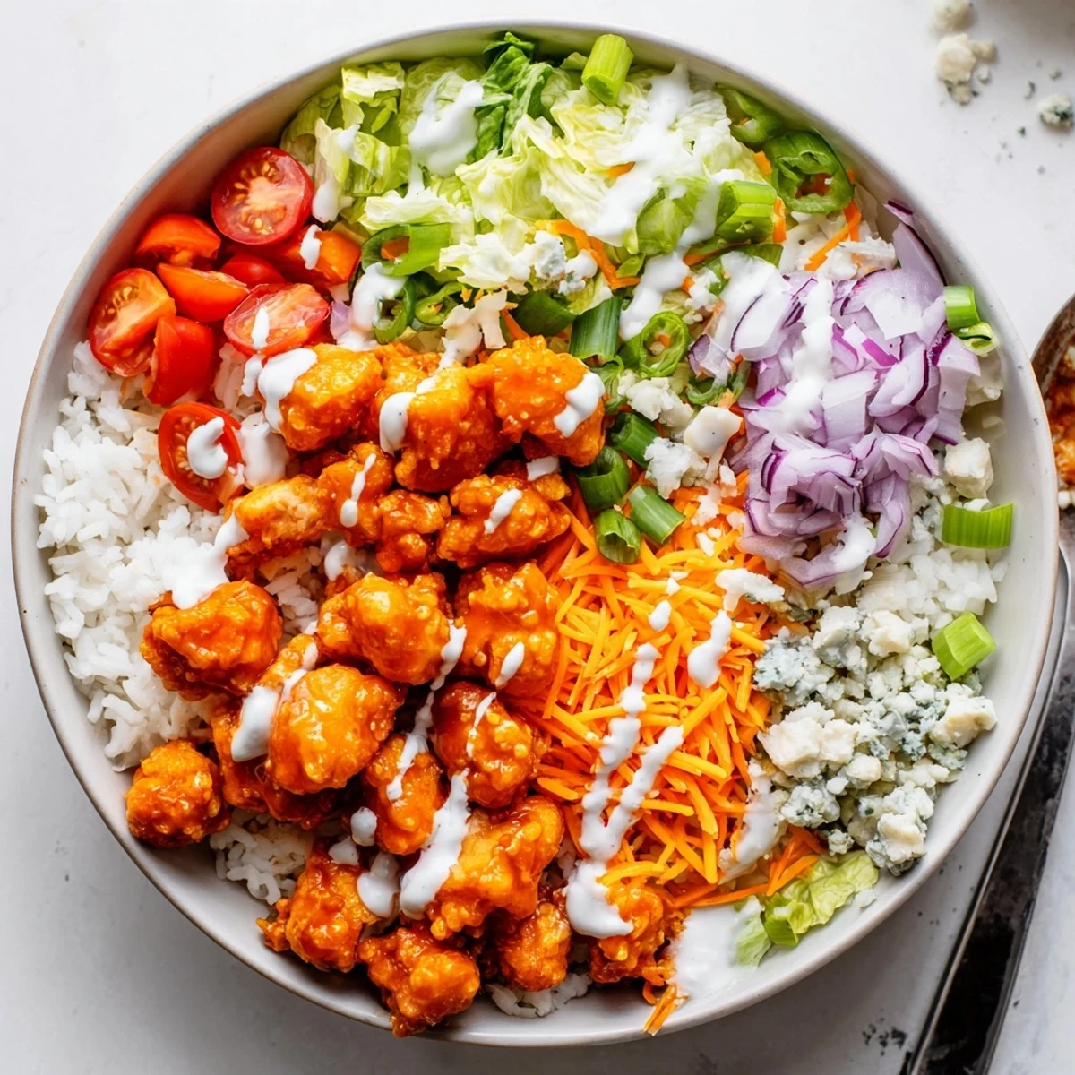 Sizzling Buffalo Chicken Bowls feature golden chicken pieces tossed in spicy sauce, drizzled with creamy ranch over fluffy rice for a hearty meal.