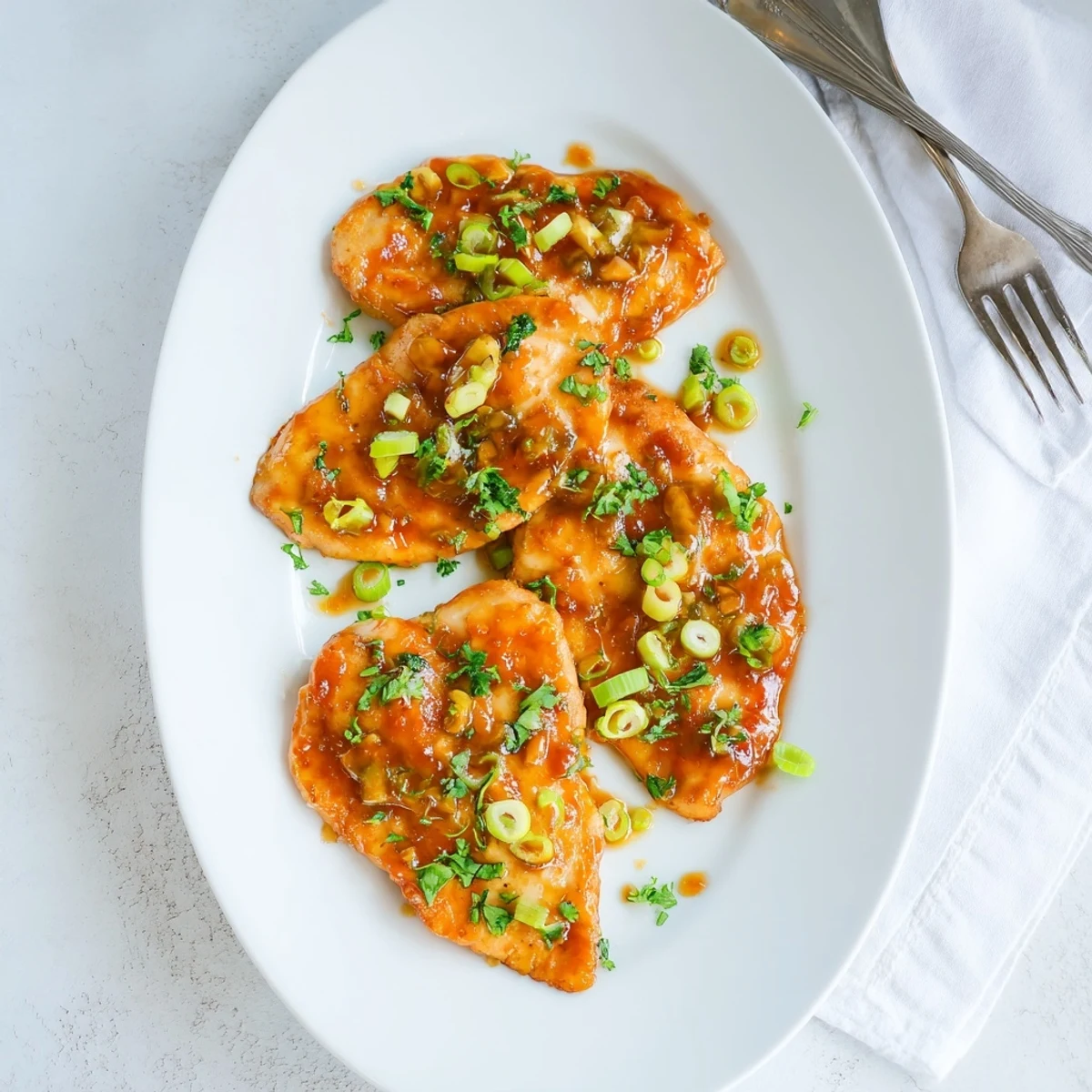 Close-up of juicy Classic Apricot Chicken with a glossy, sweet-and-savory sauce, topped with sliced green onions and parsley, ideal for a weeknight family meal served over steamed rice.