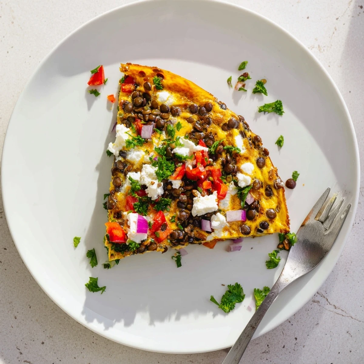 Freshly baked Healthy Lentil and Feta Frittata sliced on a white plate, showcasing tender lentils and creamy feta.