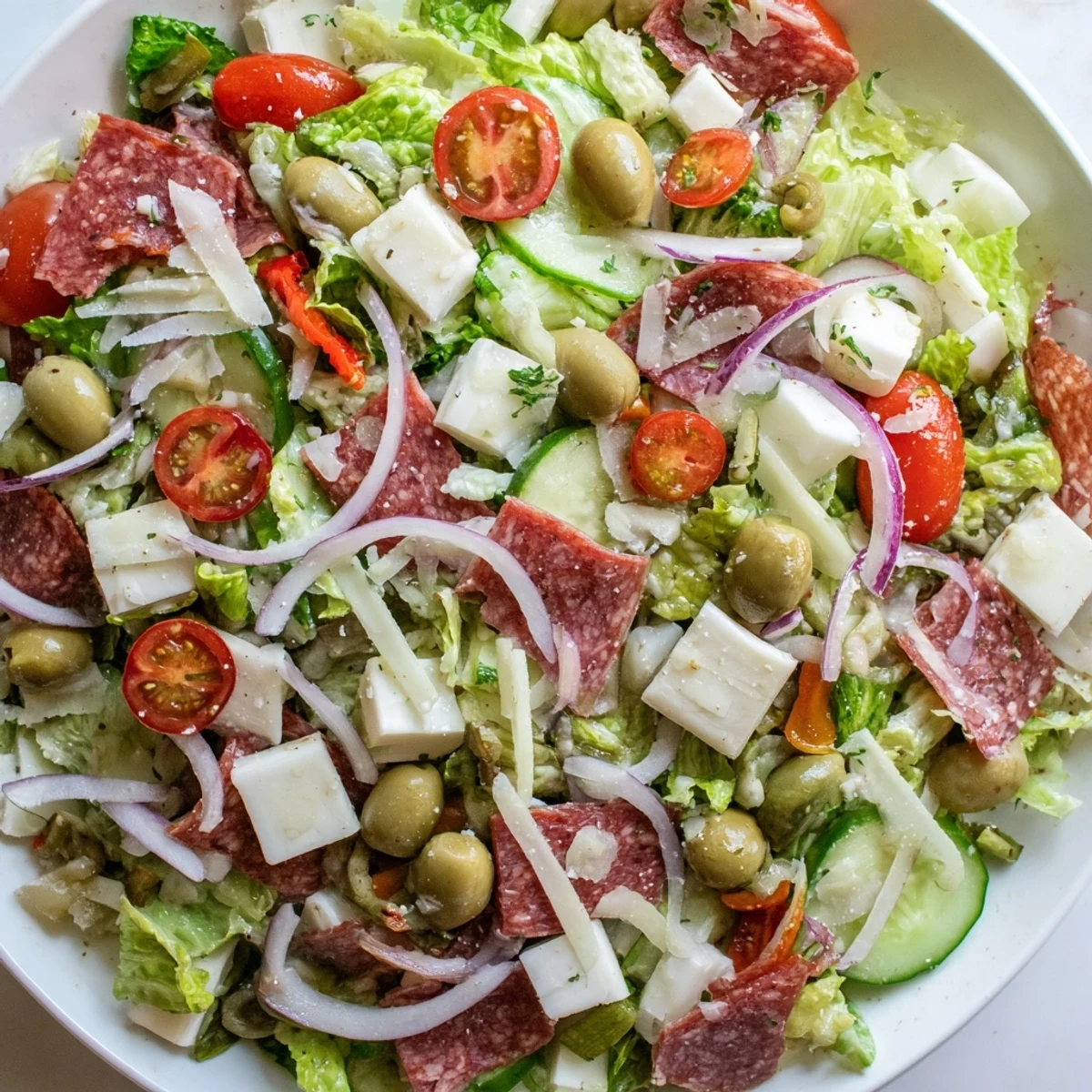 Fresh Italian chopped salad featuring romaine, cherry tomatoes, olives, and pepperoncini drizzled with tangy homemade Italian dressing