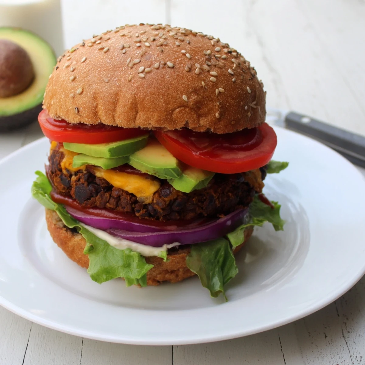 Golden epic black bean burger patty topped with crisp lettuce, red onion, and creamy mayo on sesame seed bun