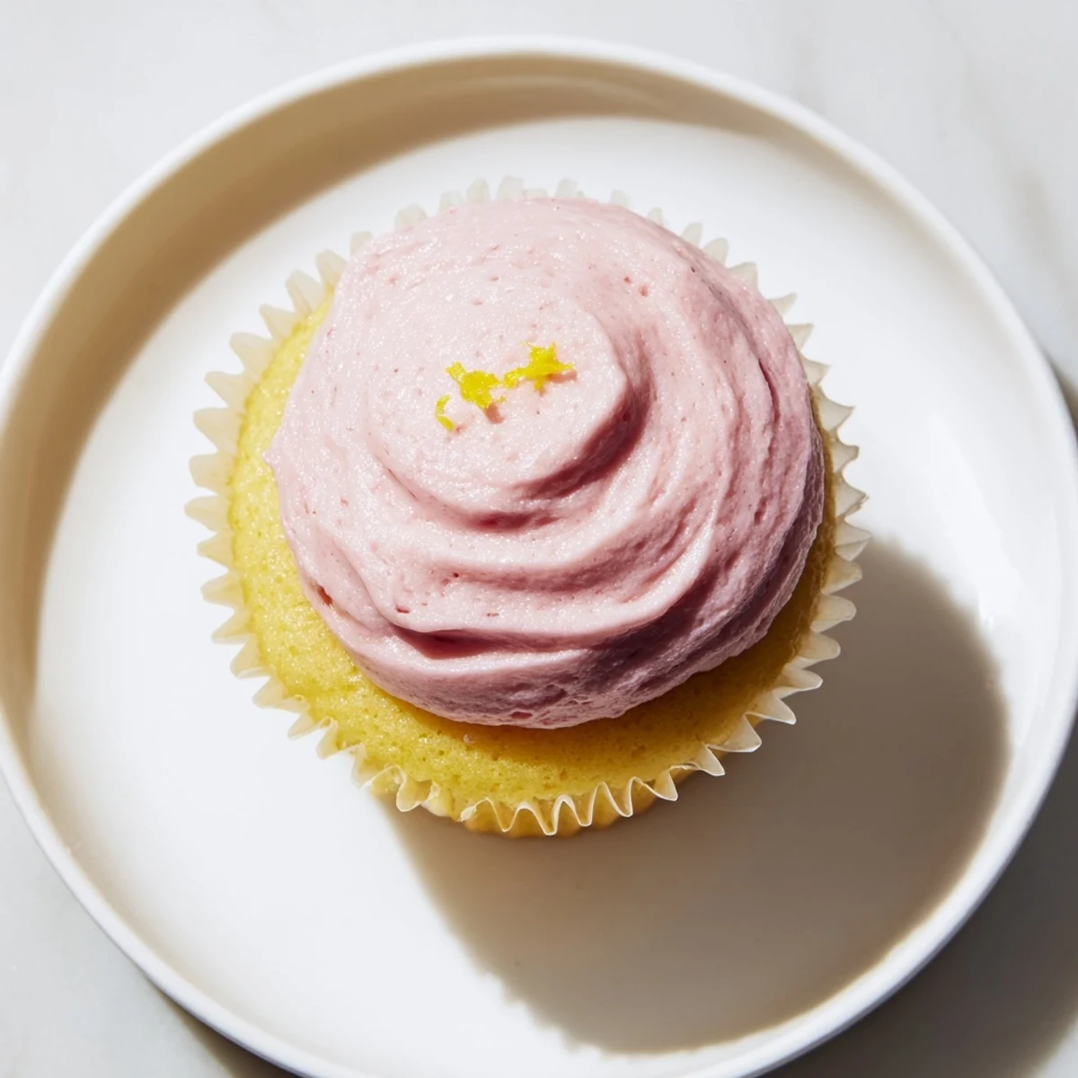 Golden lemon cupcakes topped with swirls of fresh pink strawberry buttercream frosting