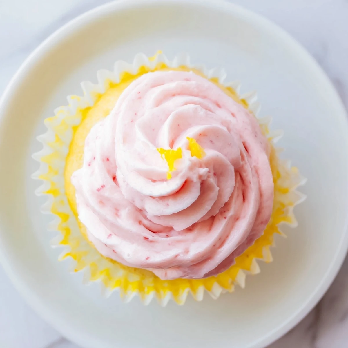 Zesty lemon cupcakes garnished with vibrant strawberry buttercream for a fruity spring dessert