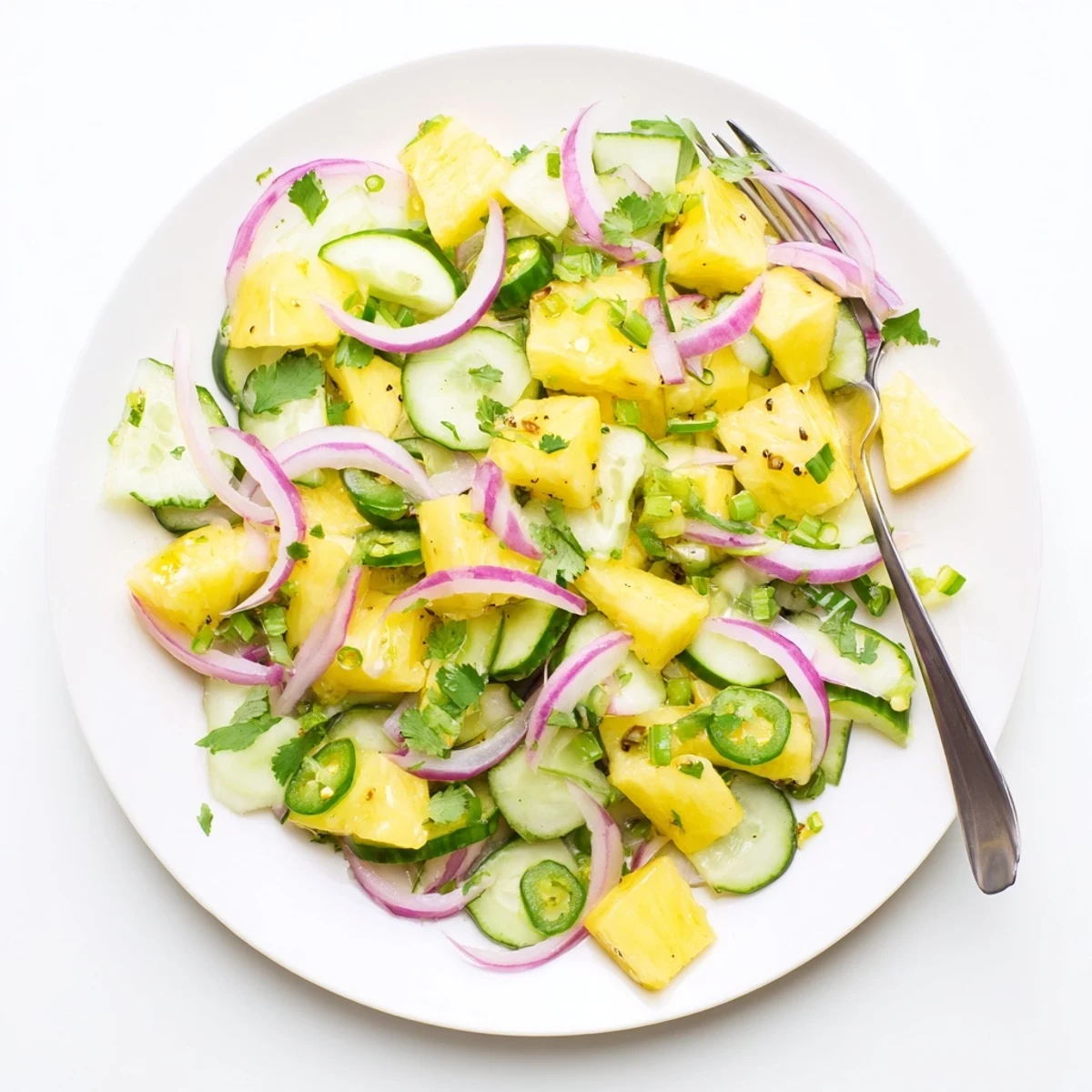 Colorful tropical pineapple cucumber salad with diced red onion and fresh cilantro garnish