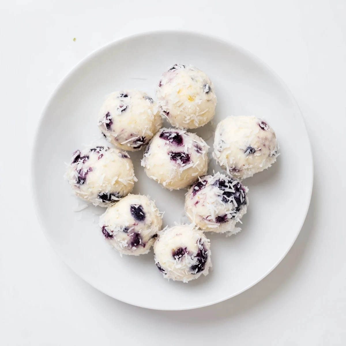No-bake blueberry cheesecake protein bites with visible fruit pieces ready for chilling