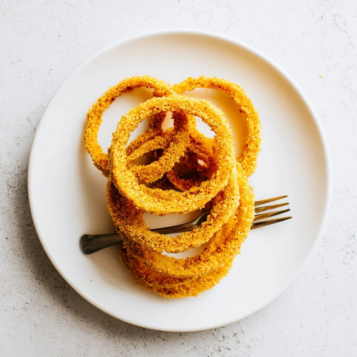 Golden brown crispy onion ring chips arranged on a white plate ready for dipping