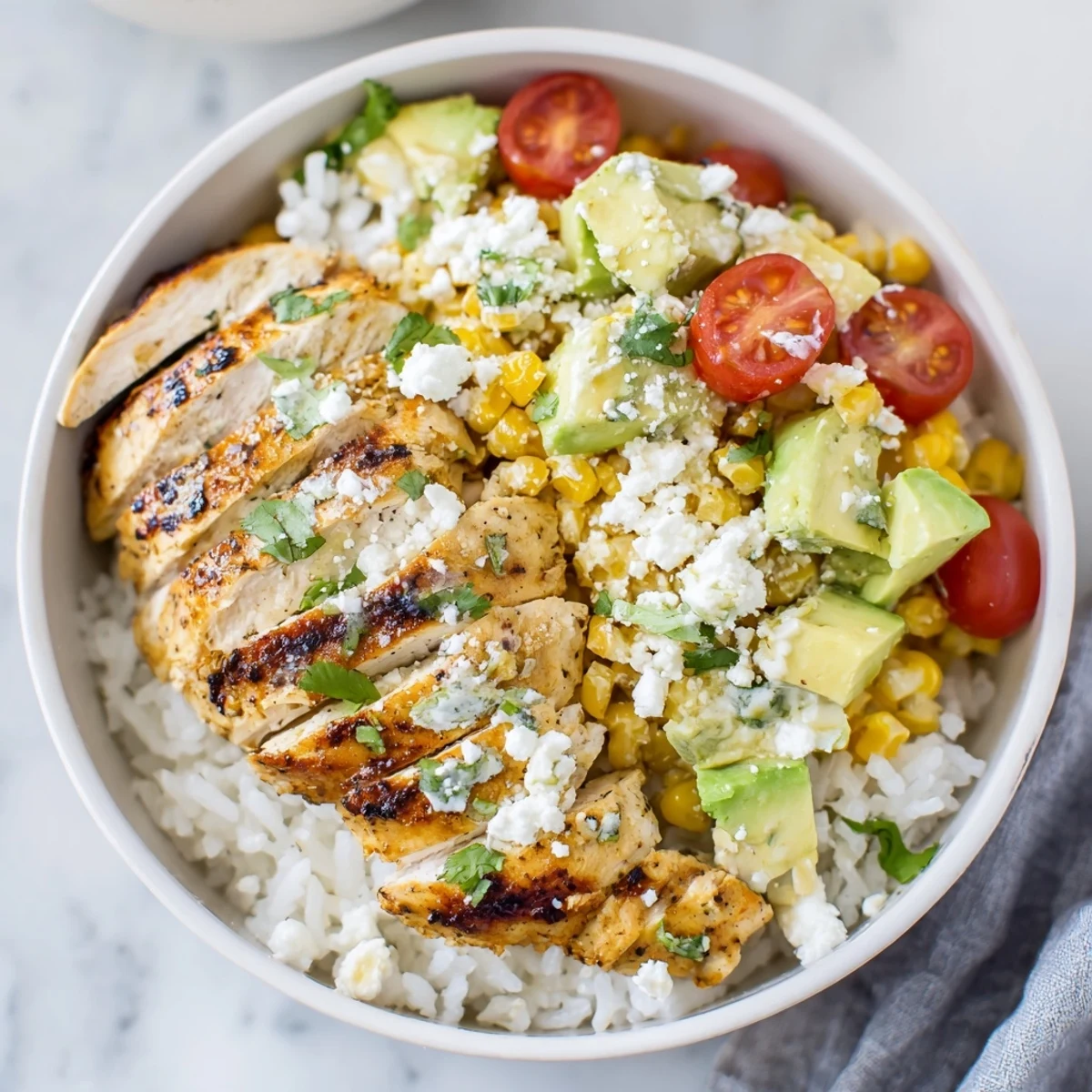 Vibrant street corn chicken and rice bowl with grilled chicken, creamy corn, avocado, and fresh cilantro toppings