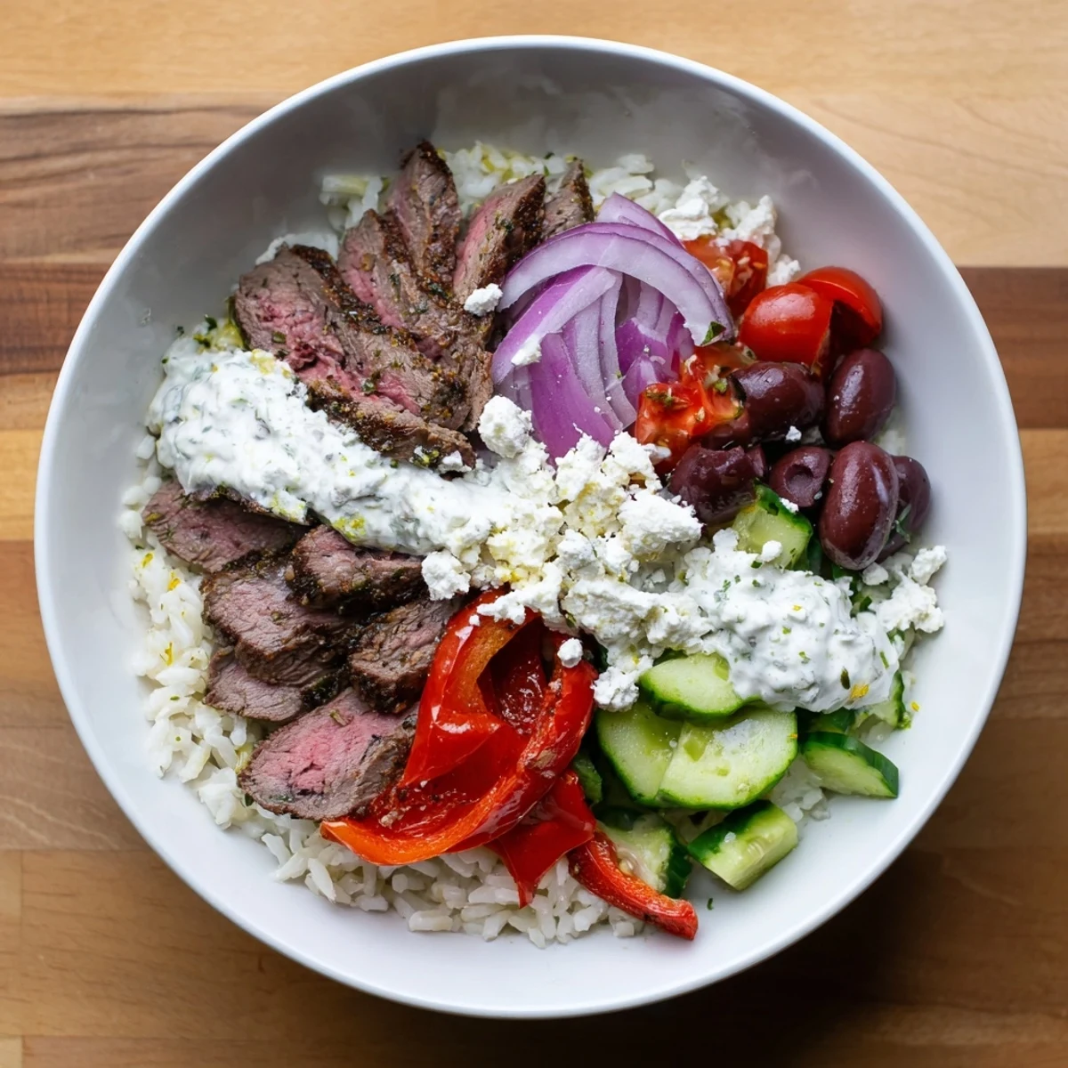 Mediterranean steak bowl loaded with cherry tomatoes, cucumber, olives and tender grilled steak slices
