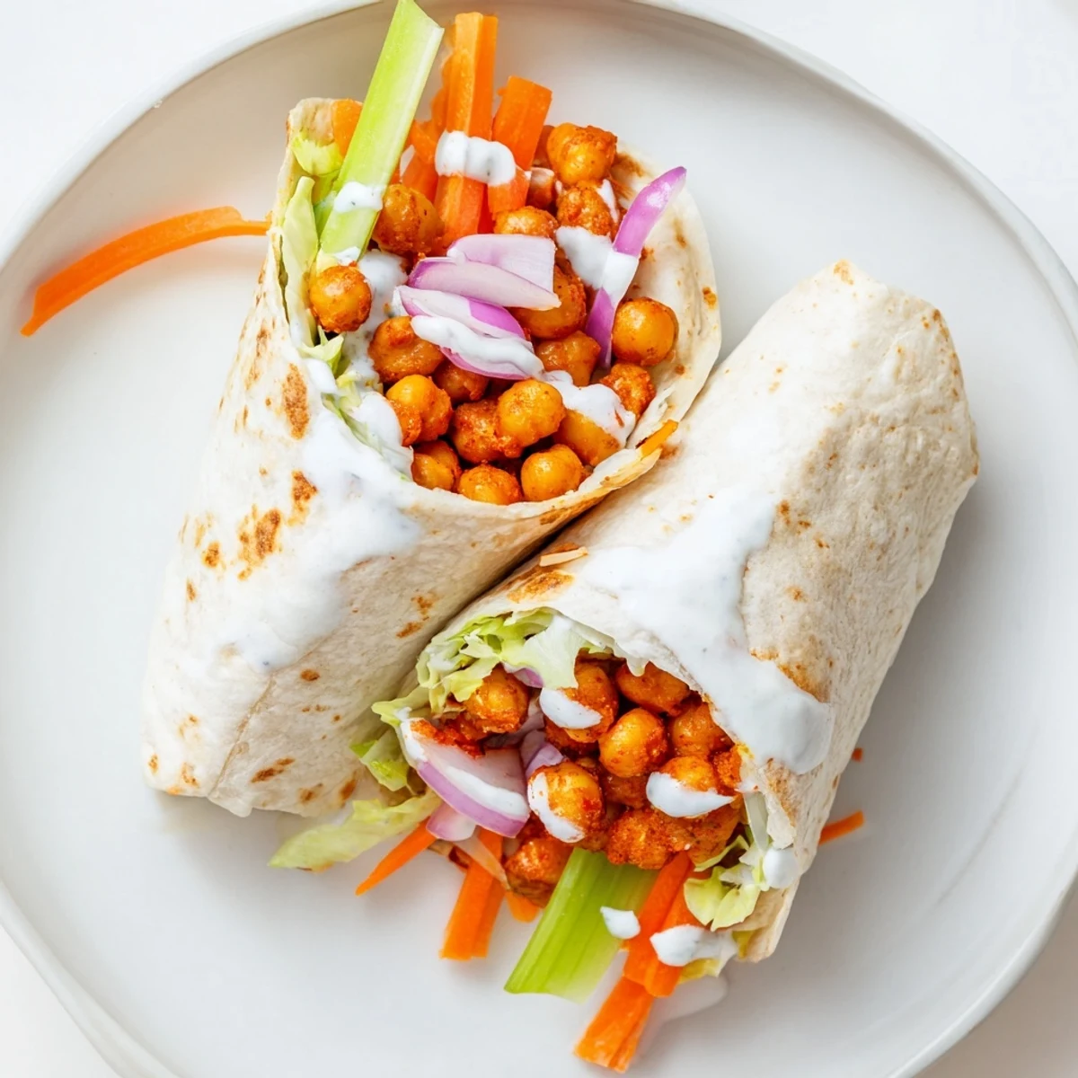 Flour tortilla wrap filled with spicy buffalo chickpeas, crisp lettuce, shredded carrots, and creamy ranch dressing
