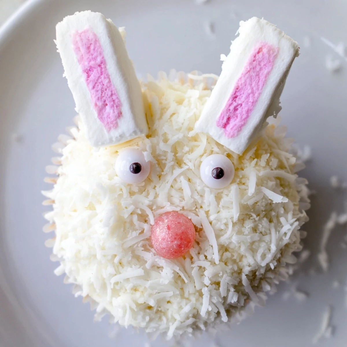 Frosted vanilla bunny cupcakes decorated with candy eyes and pink jelly bean noses