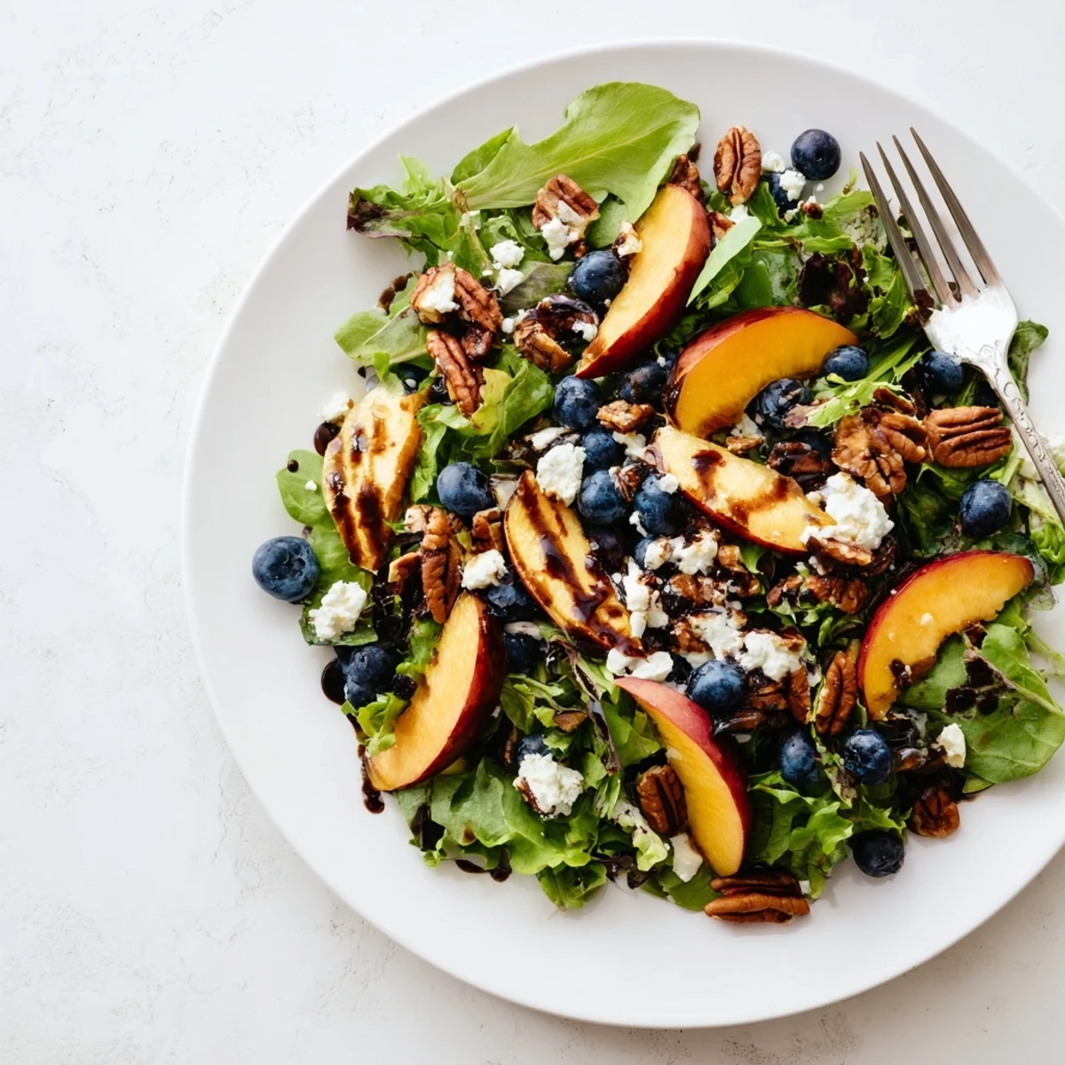 Vibrant summer blueberry peach feta salad topped with creamy cheese crumbles and toasted pecans