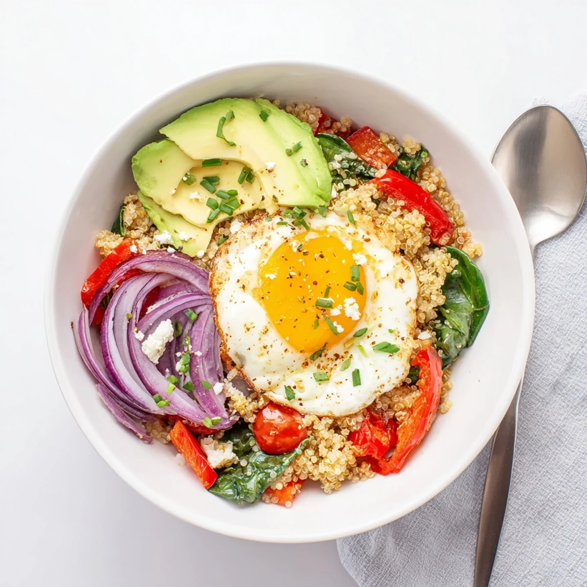 Protein-rich savory quinoa breakfast bowl featuring wilted spinach cherry tomatoes and perfectly cooked sunny-side up egg