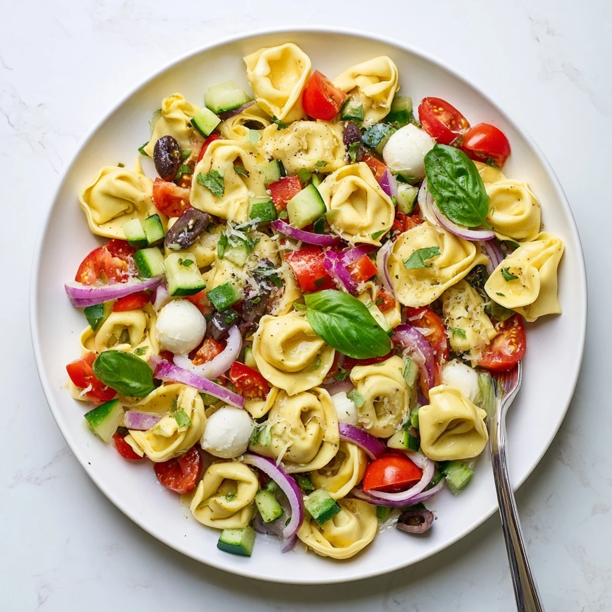 Colorful tortellini salad with cherry tomatoes, cucumber, and mozzarella tossed in zesty Italian dressing