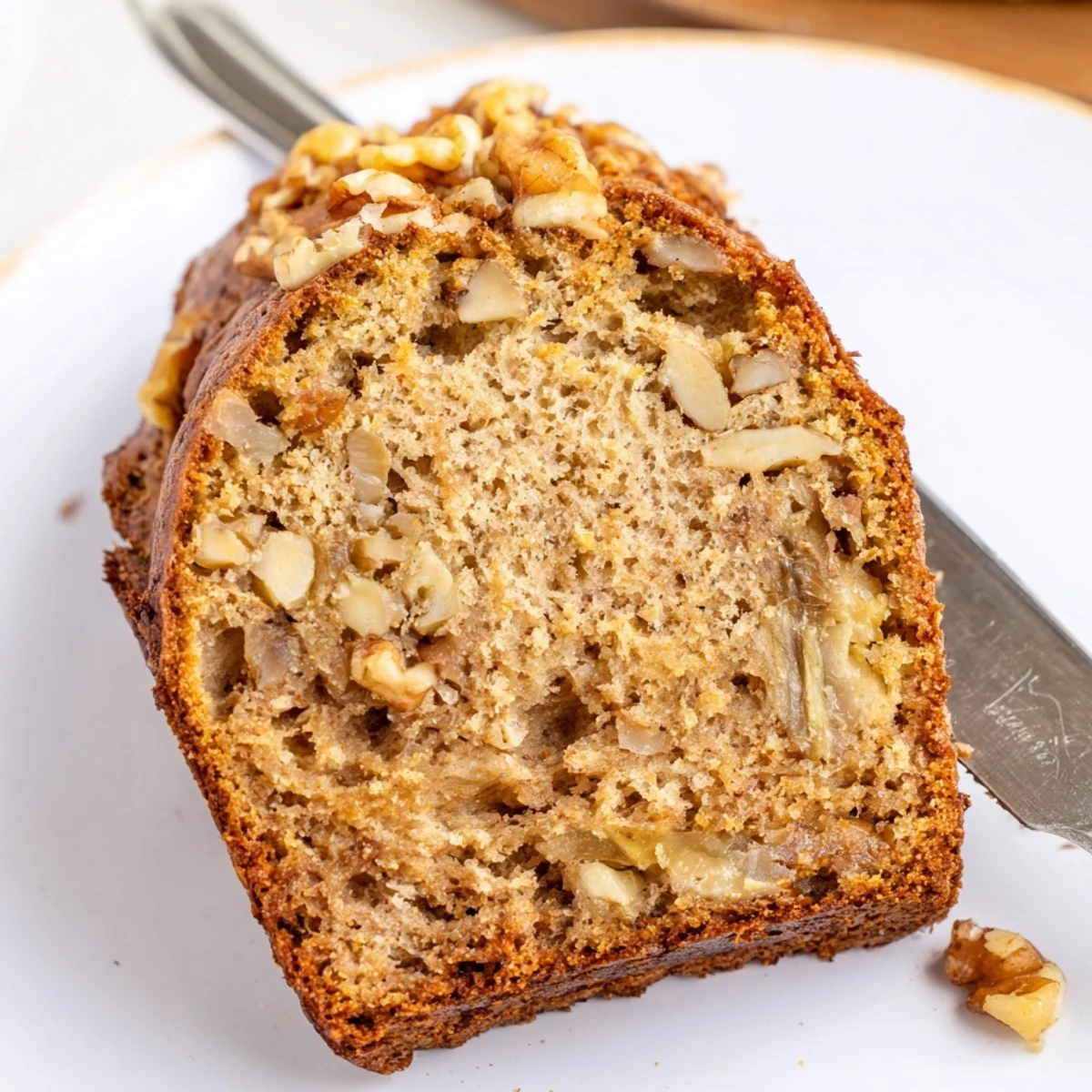 Warm slice of Nana's Secret Banana Nut Bread drizzled with butter on a ceramic plate