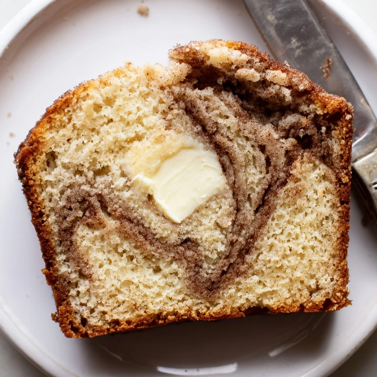 Golden snickerdoodle banana bread sliced on a rustic board with a cinnamon-sugar crust