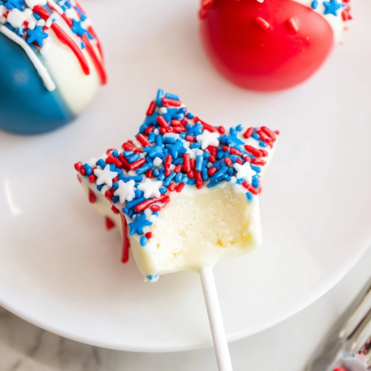 Plate of Fourth Of July Star Cheesecake Pops with red, white, blue sprinkles