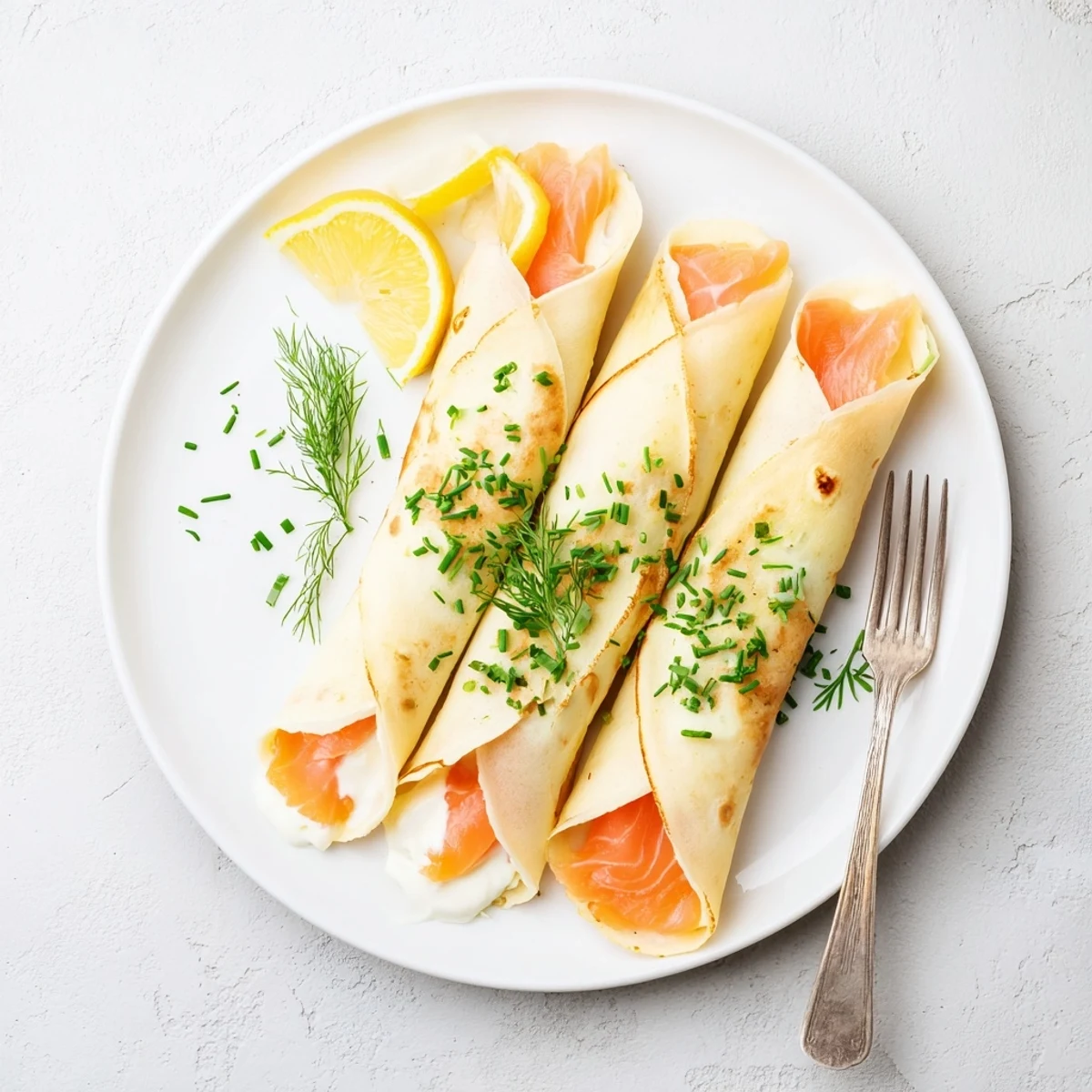 Brunch ready crepes filled with silky smoked salmon and herb cream cheese garnished with lemon wedges
