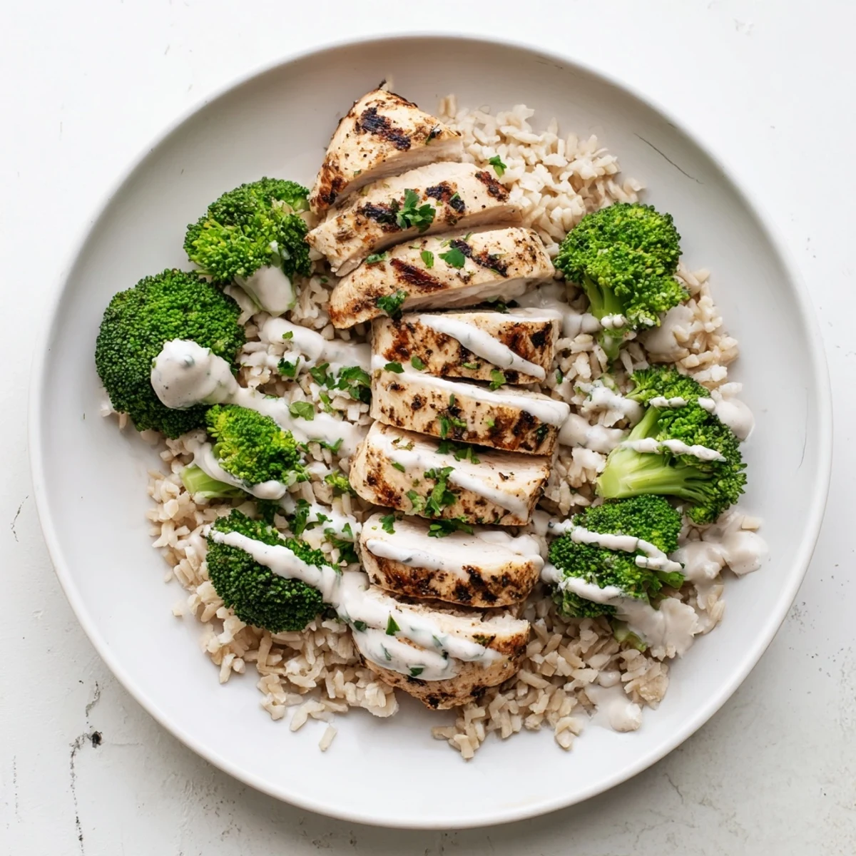 Protein-rich grilled chicken breast served with crisp-tender broccoli and luscious garlic sauce, garnished with fresh parsley and lemon.