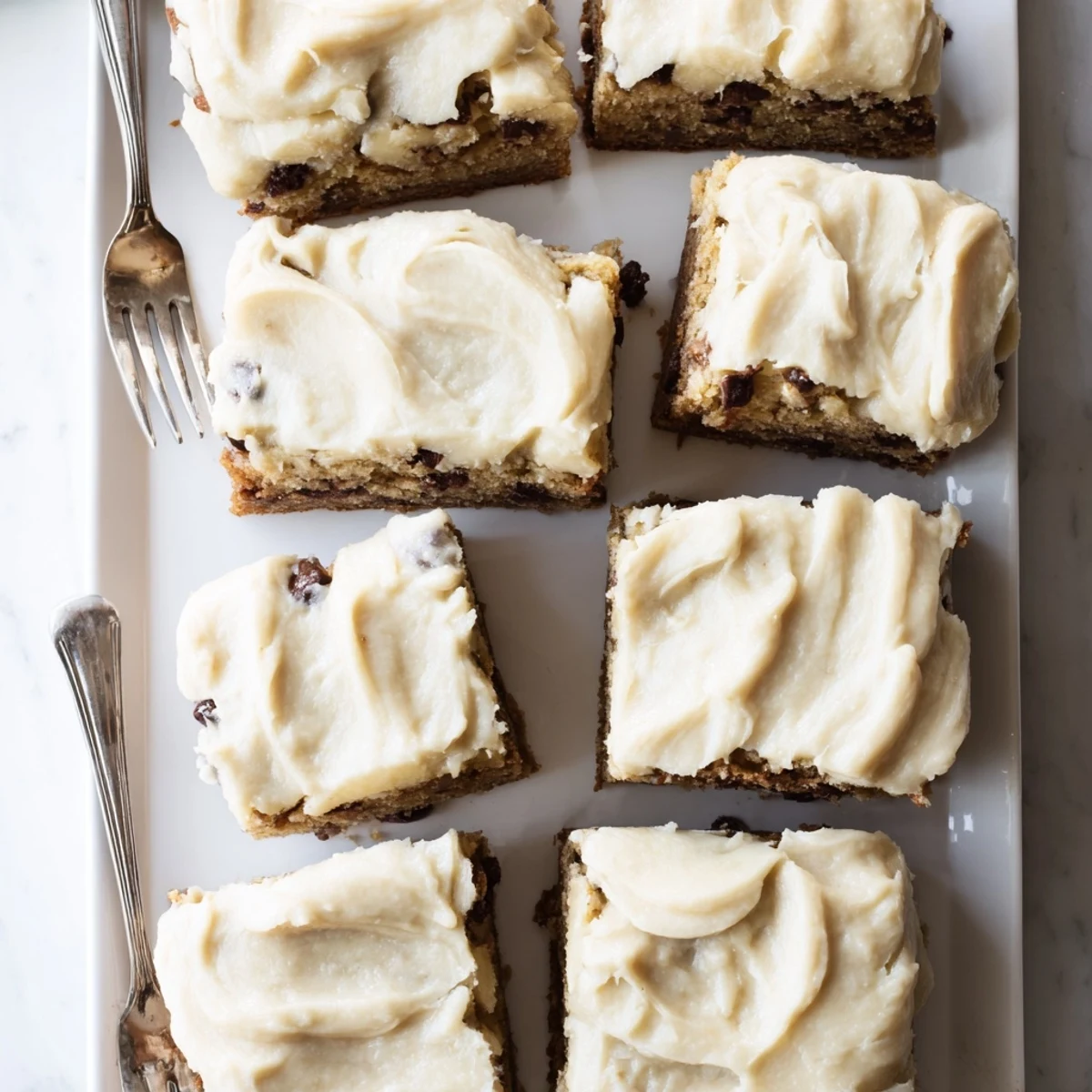 Thick banana bread brownies swirled with rich brown butter frosting on a white plate