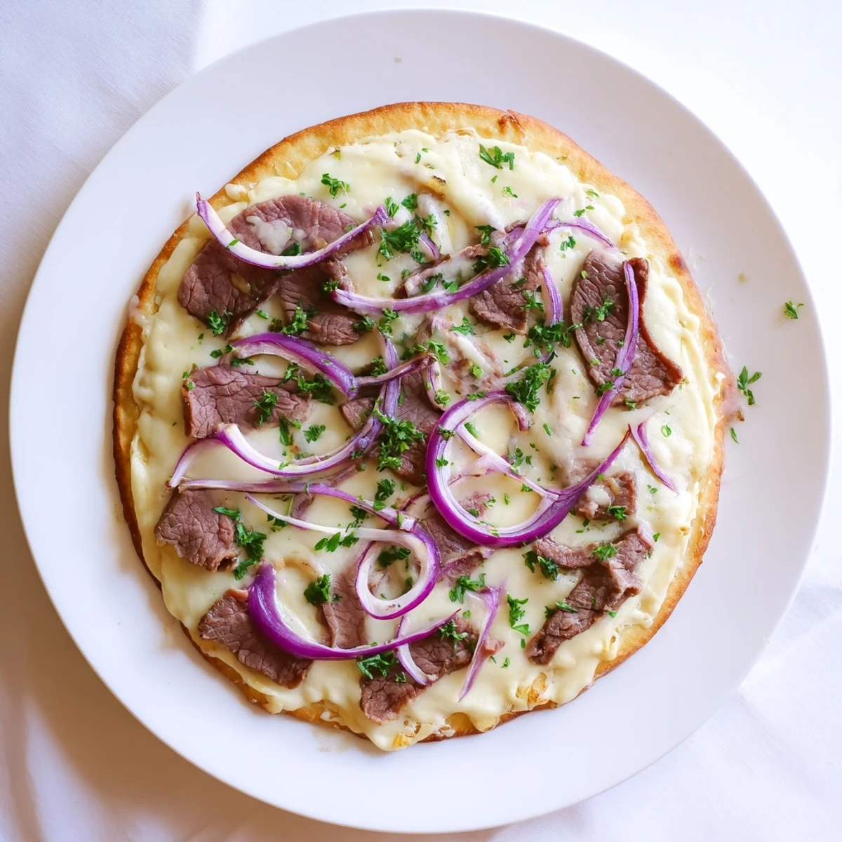 Homemade Beef Alfredo Pizza featuring golden crust topped with creamy white sauce, savory beef slices, and melted mozzarella cheese