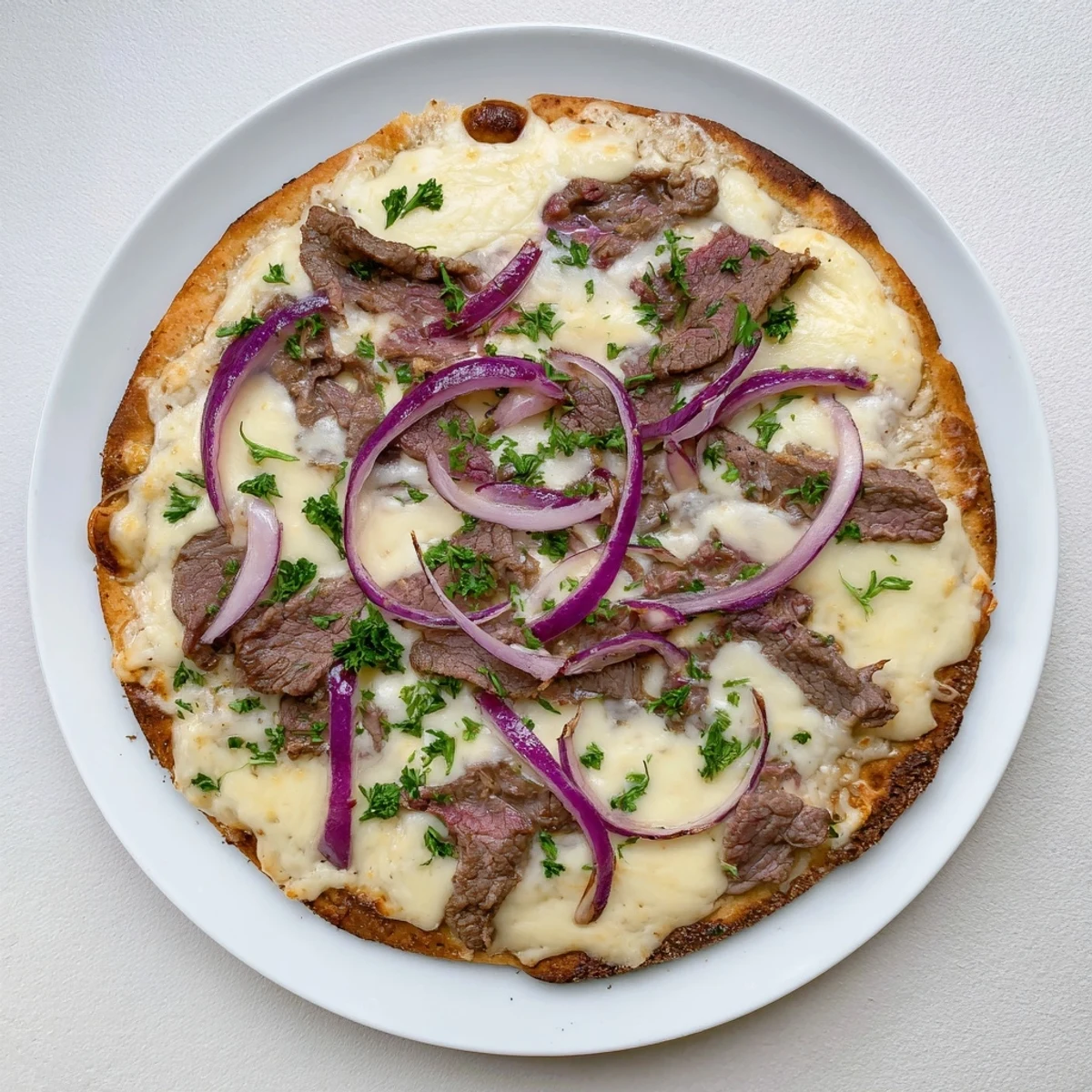 Freshly baked Beef Alfredo Pizza displaying layered toppings of seasoned beef, red onion, and gooey cheeses over a smooth white sauce base