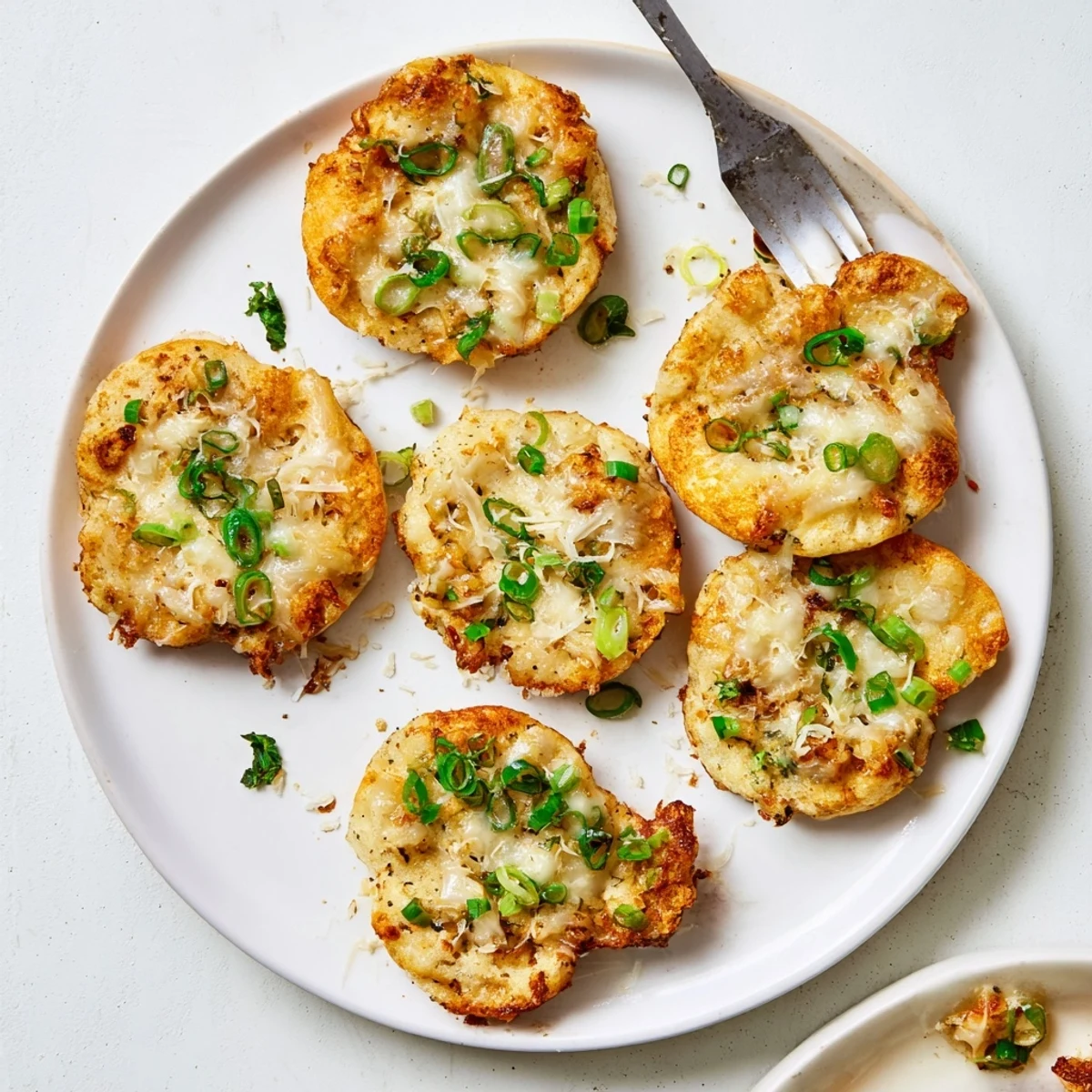 Pan fried keto chicken fritters stacked attractively with visible golden crust and shredded cheese texture
