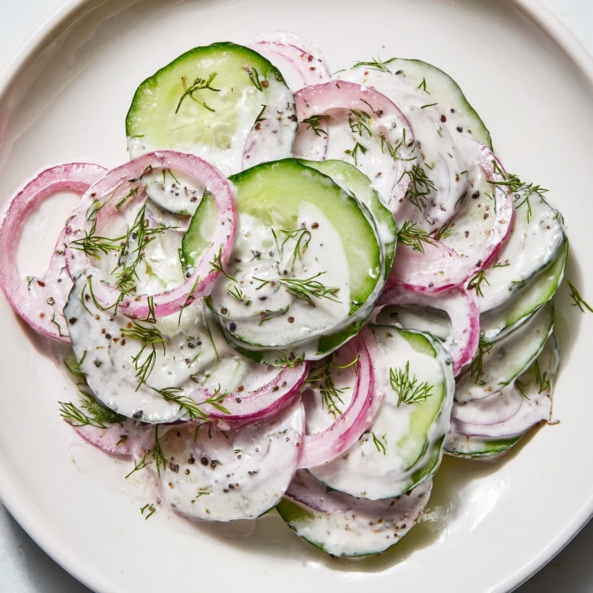 Light and tangy cucumber dill salad served in white bowl with sour cream dressing