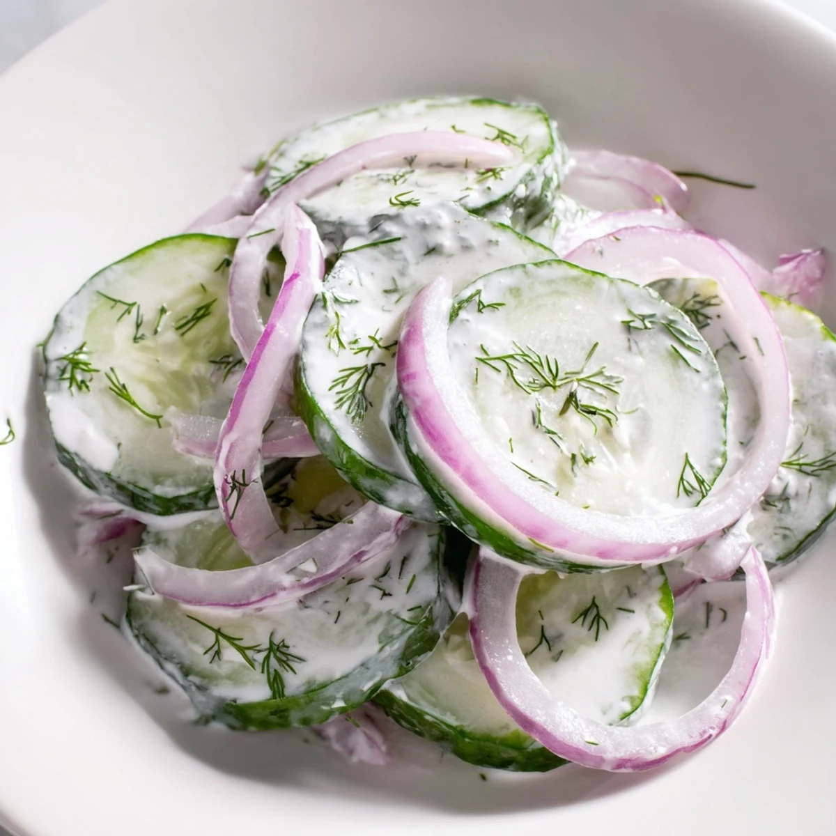 Fresh cucumber dill salad with thinly sliced cucumbers in creamy dressing and chopped dill