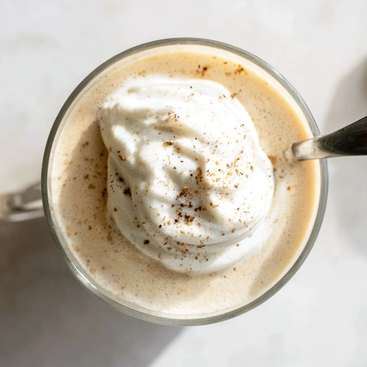 Creamy keto eggnog topped with whipped cream and dusted with freshly ground nutmeg
