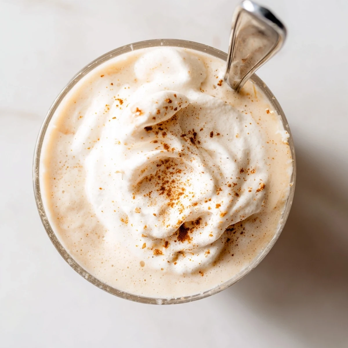 Glass of low-carb holiday eggnog garnished with cinnamon stick on festive table setting