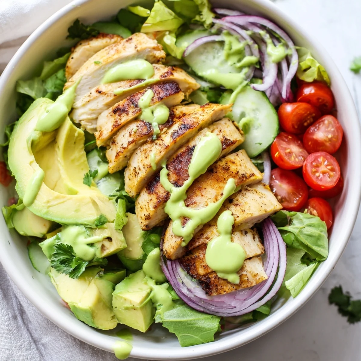 Healthy avocado grilled chicken salad bowl layered with juicy meat and vibrant garden vegetables