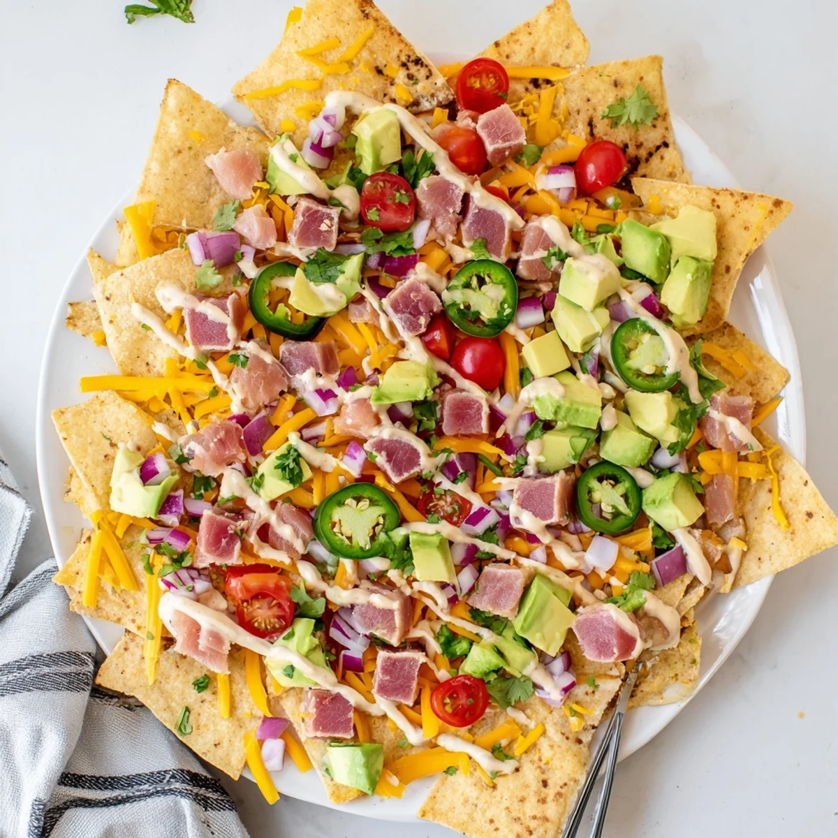 Serving platter of tuna nachos deluxe featuring melted cheese colorful cherry tomatoes diced red onion and seared rare tuna cubes