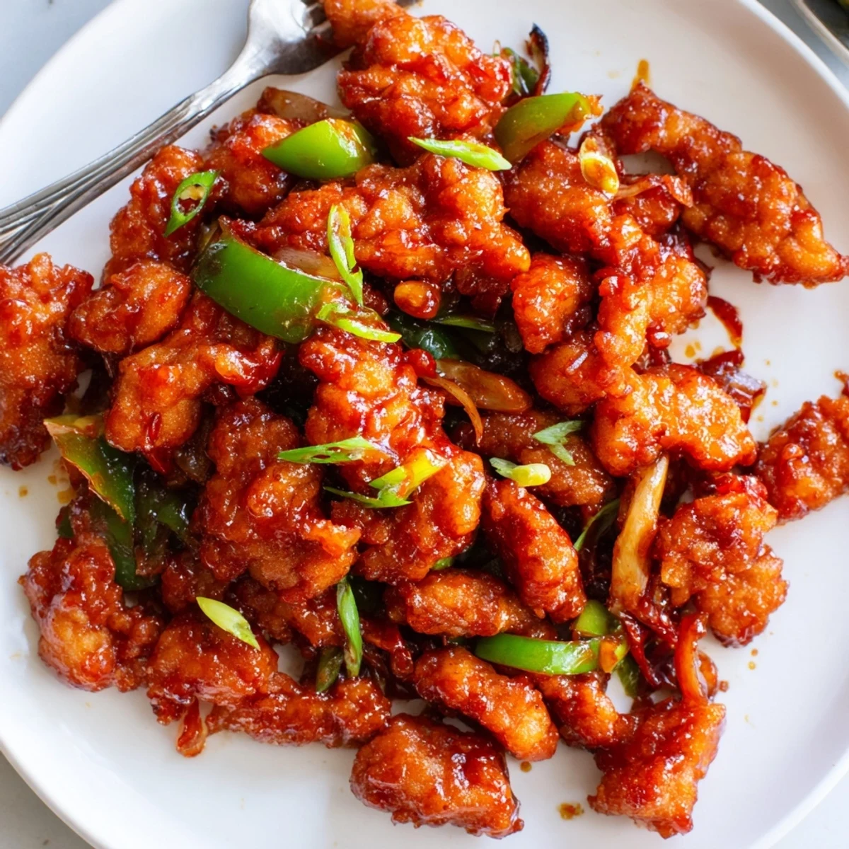 Plate of Flavorful Chilli Chicken Indo Chinese with glossy sauce and scallions