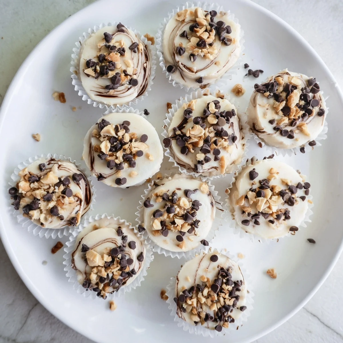 Frozen Greek yogurt peanut butter bites displayed on a marble surface with coconut flakes and chocolate chip toppings glistening