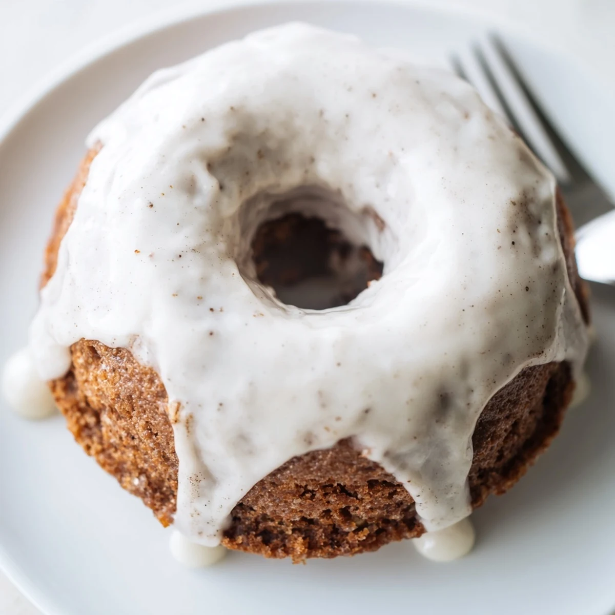 Moist baked banana bread donuts with cinnamon spices cooling on a white plate