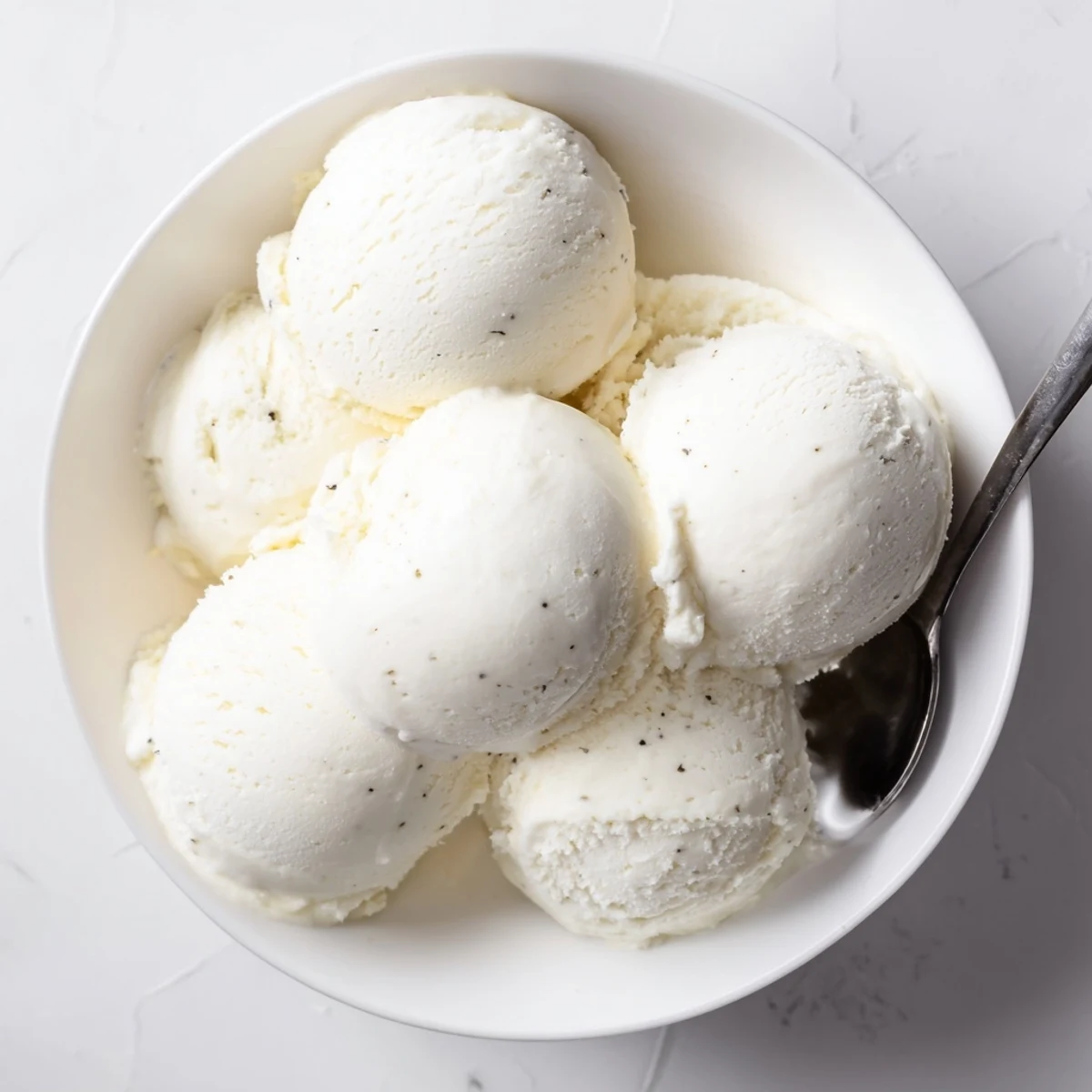 Creamy homemade vanilla ice cream recipe scooped into a bowl with fresh berries
