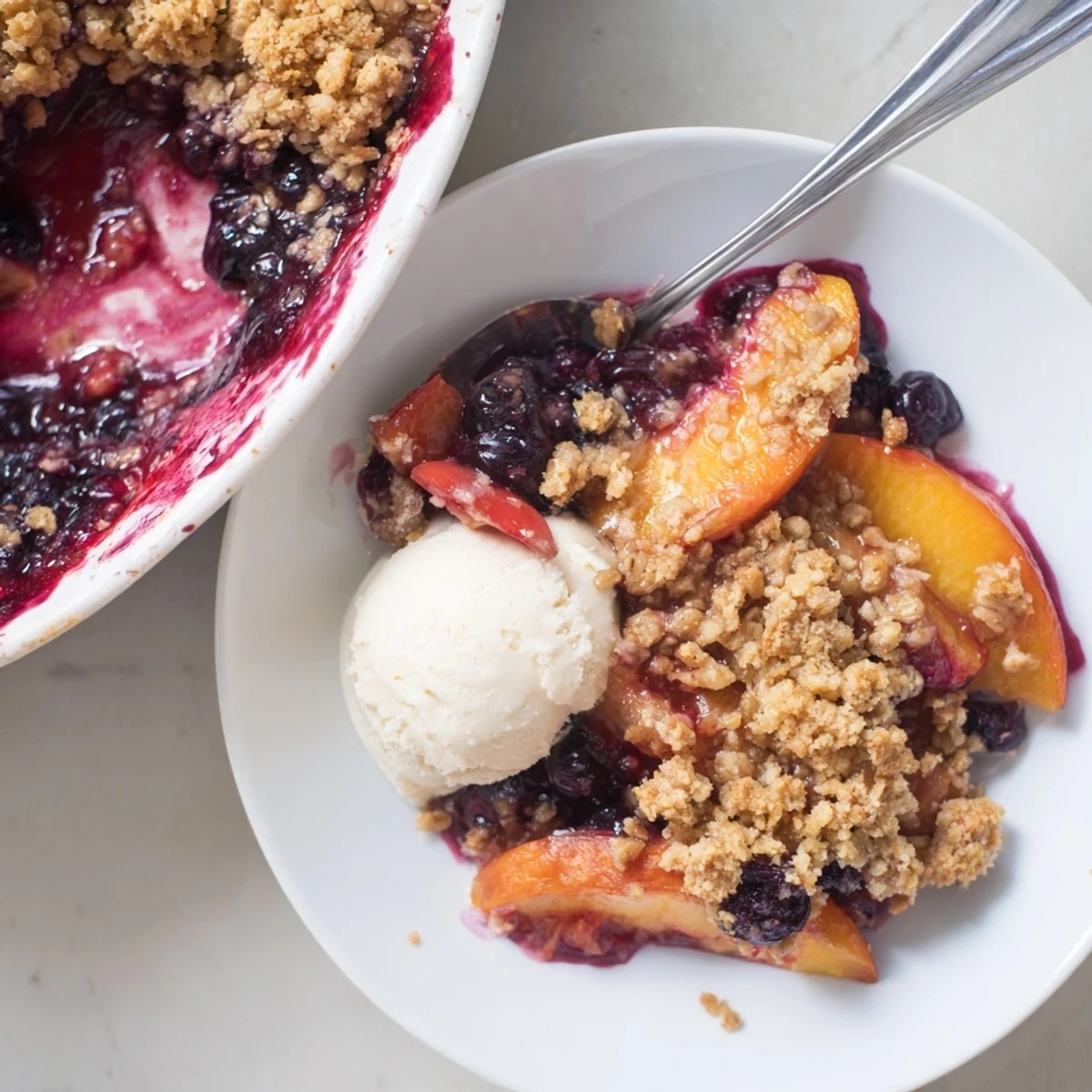 Warm Blueberry Peach Crumble bubbling with juicy fruit and golden oat topping.