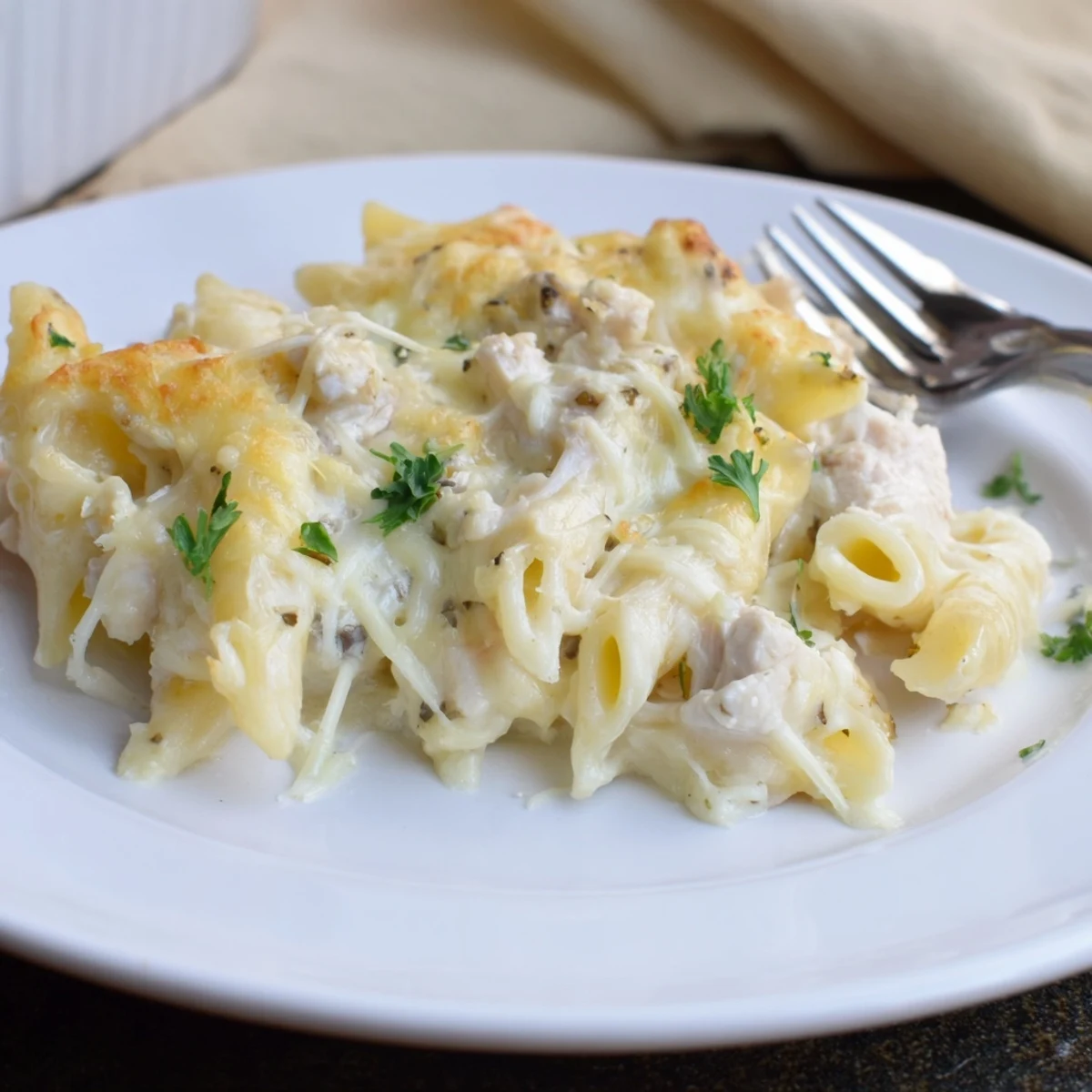 Bubbling golden Creamy Chicken Alfredo Bake With Mozzarella Crust, fragrant parsley garnish.