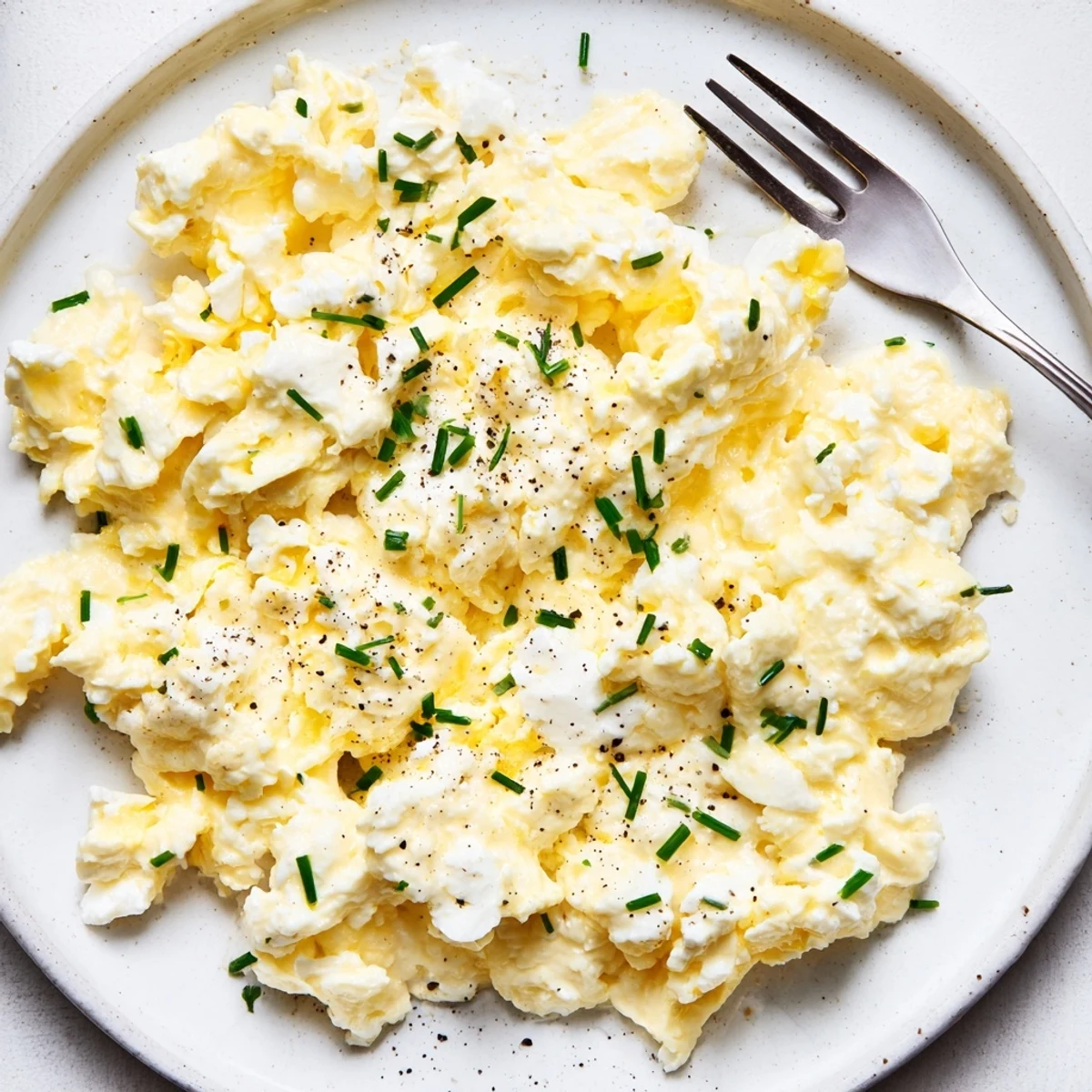 Silky scrambled eggs with cottage cheese and chives, butter aroma rising