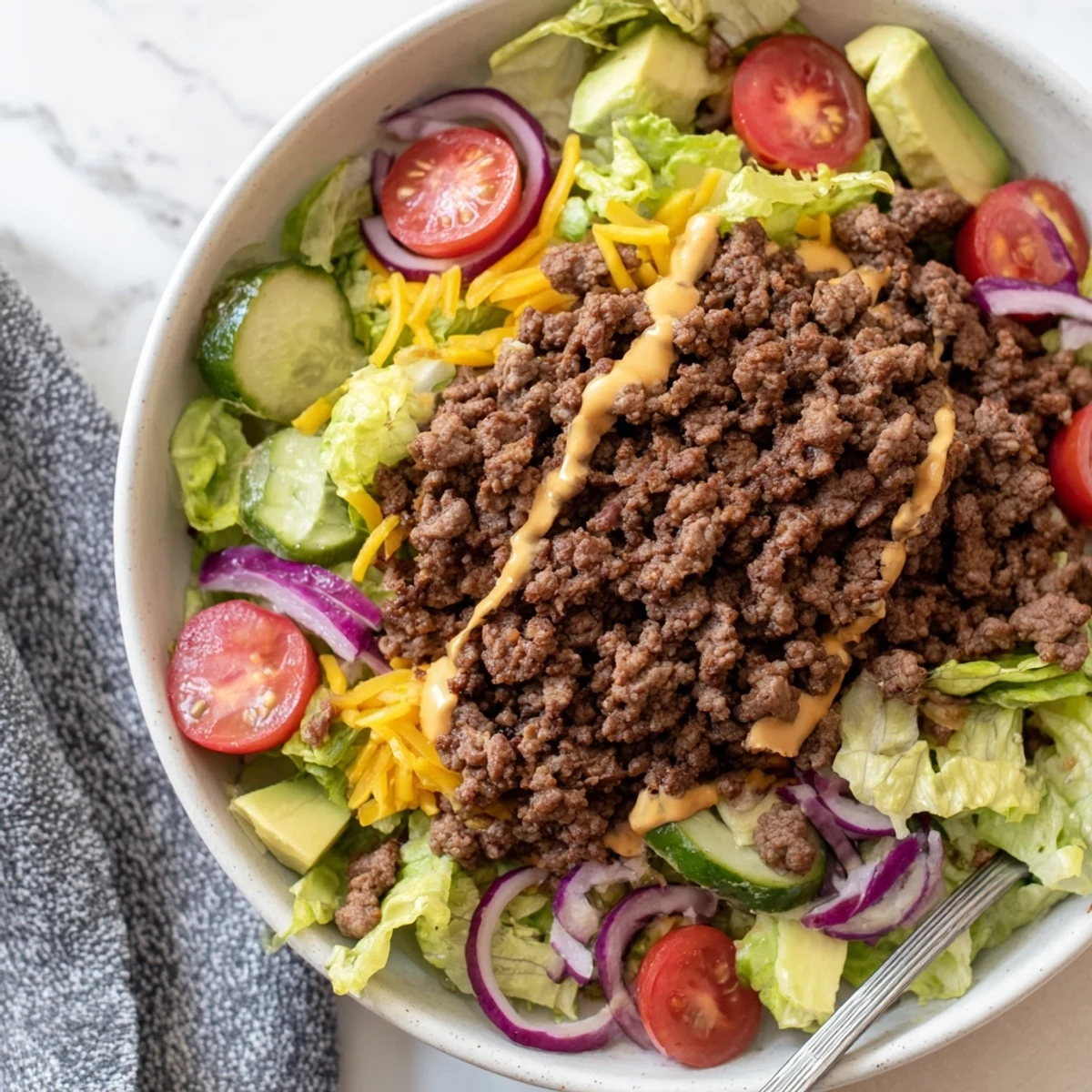 Savory Protein Packed Burger Bowls topped with creamy avocado, pickles, and cheese